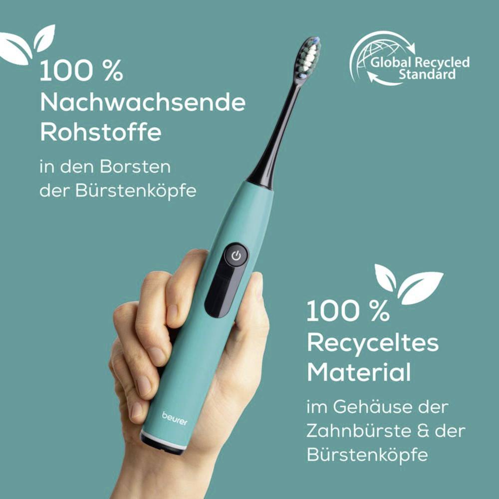 Eine Hand hält eine türkisfarbene Zahnbürste mit deutschem Text, der umweltfreundliche Materialien bewirbt und die 'Global Recycled Standard'-Zertifizierung sowie Recycling-Logos trägt.