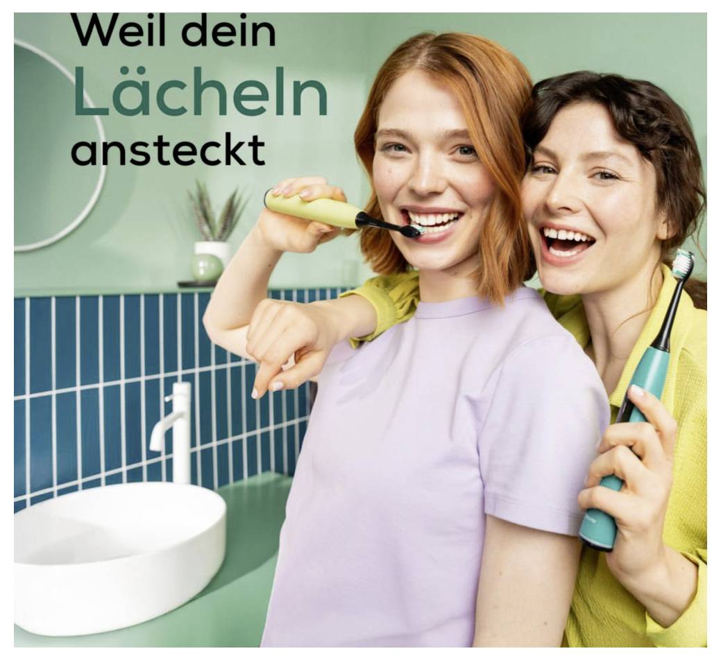 Two smiling people in a bathroom, each holding an electric toothbrush. The text reads: 'Weil dein Lächeln ansteckt'.The text is already in German and translates to English as: 