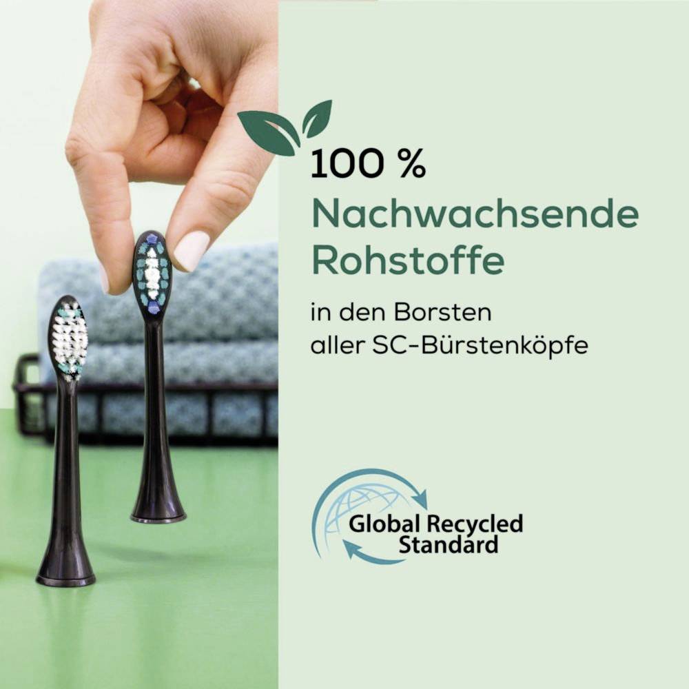 Eine Hand hält einen Zahnbürstenkopf mit zwei weiteren in der Nähe. Der Text lautet '100% Nachwachsende Rohstoffe in den Borsten aller SC-Bürstenköpfe' und zeigt das Global Recycled Standard Logo.