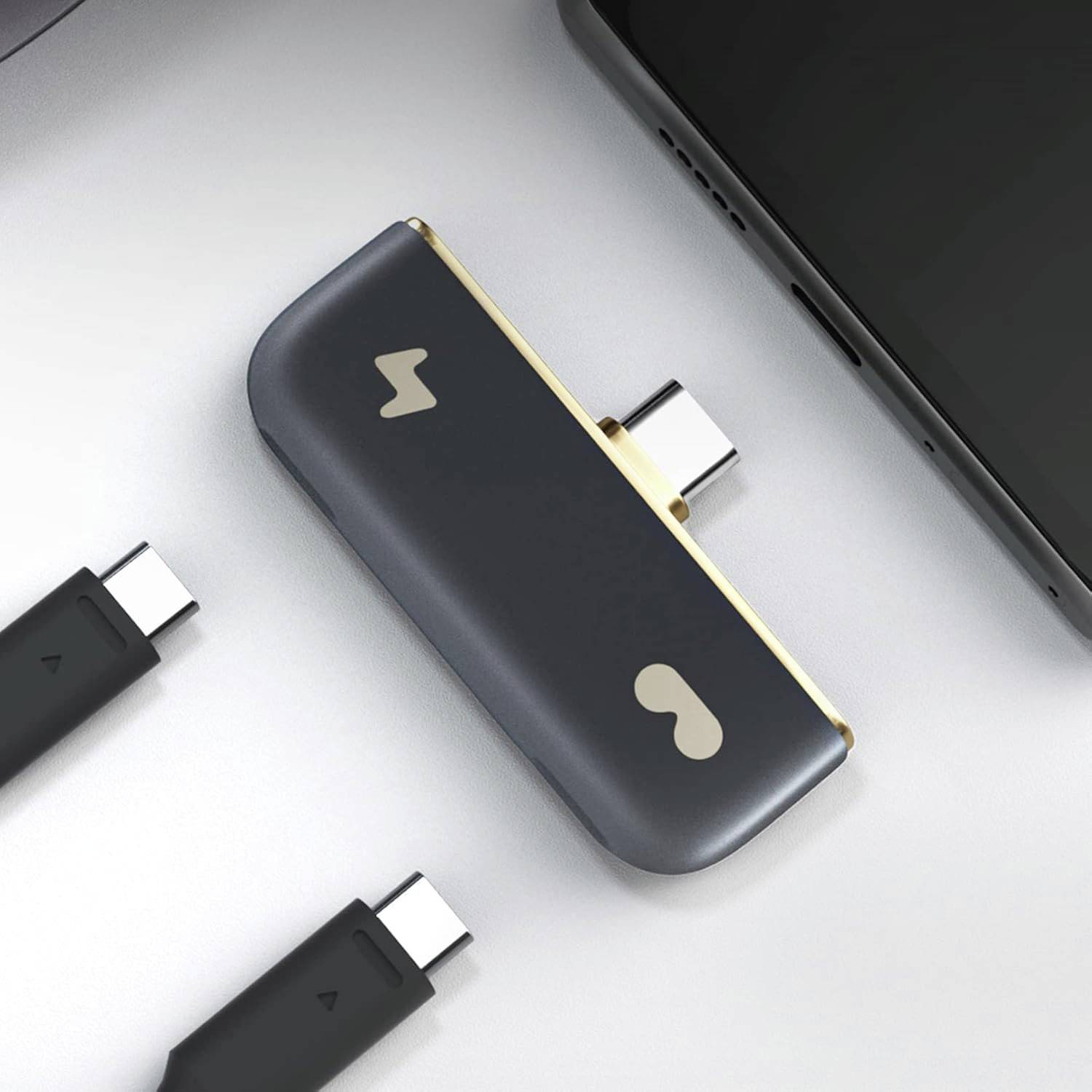 Ein Dual-Port-USB-C-Hub, der mit einem Smartphone verbunden ist, mit zusätzlichen USB-C-Kabeln in der Nähe.