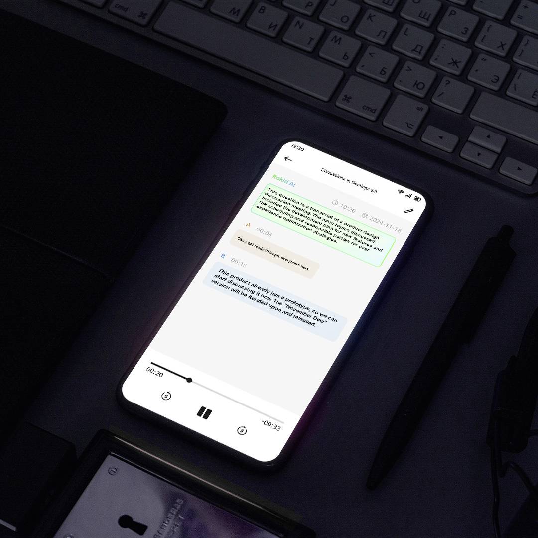 Ein Smartphone auf einem Schreibtisch zeigt einen Chat-App-Austausch zwischen zwei Nutzern, mit Erwähnung von ‚Design QA' und ‚Ryan Gosling Filmen'. Ein Play-Button ist sichtbar.