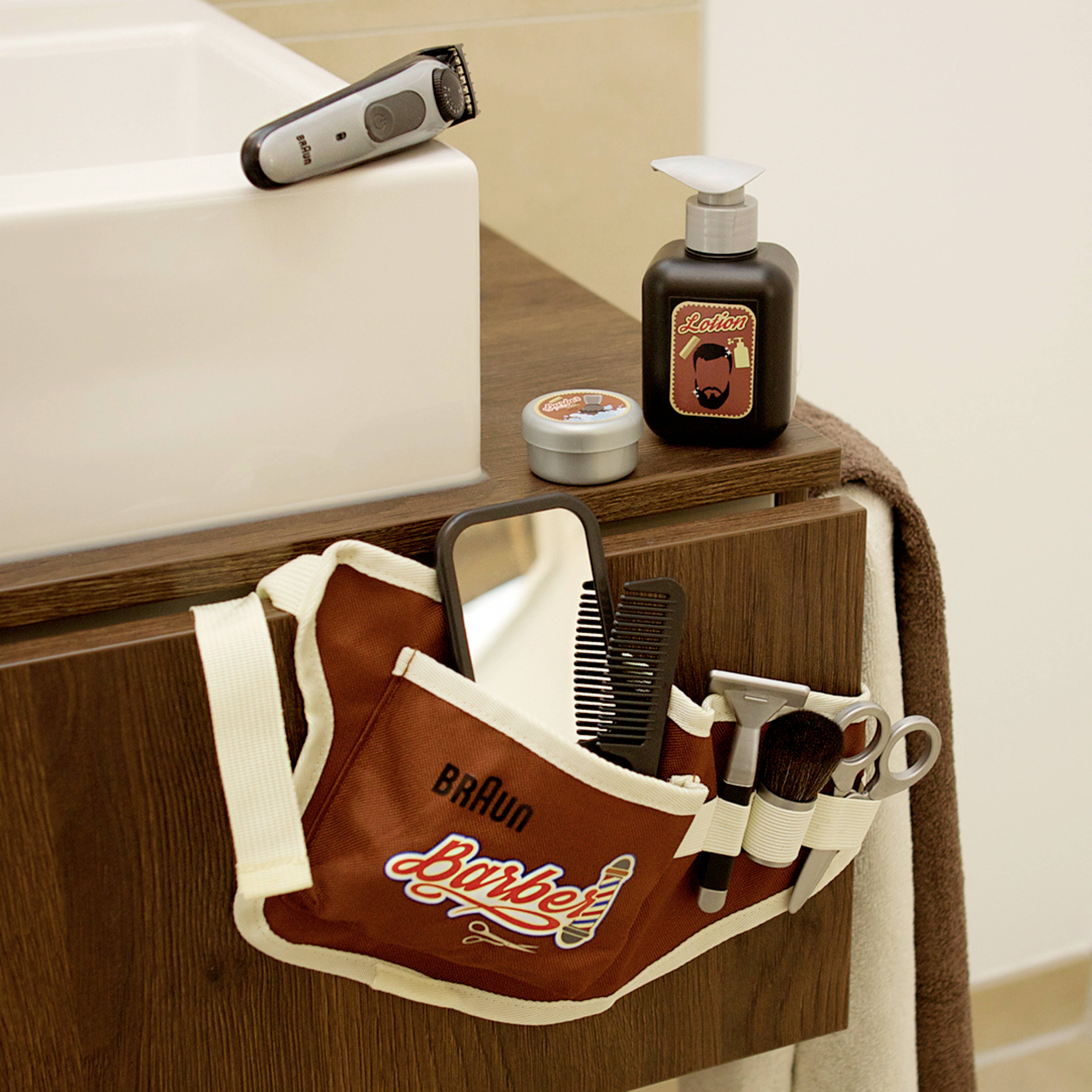 Auf der Badezimmerablage des Friseurs befinden sich ein Haarschneider, eine Bürste, ein Kamm, eine Schere und Rasierschaum.