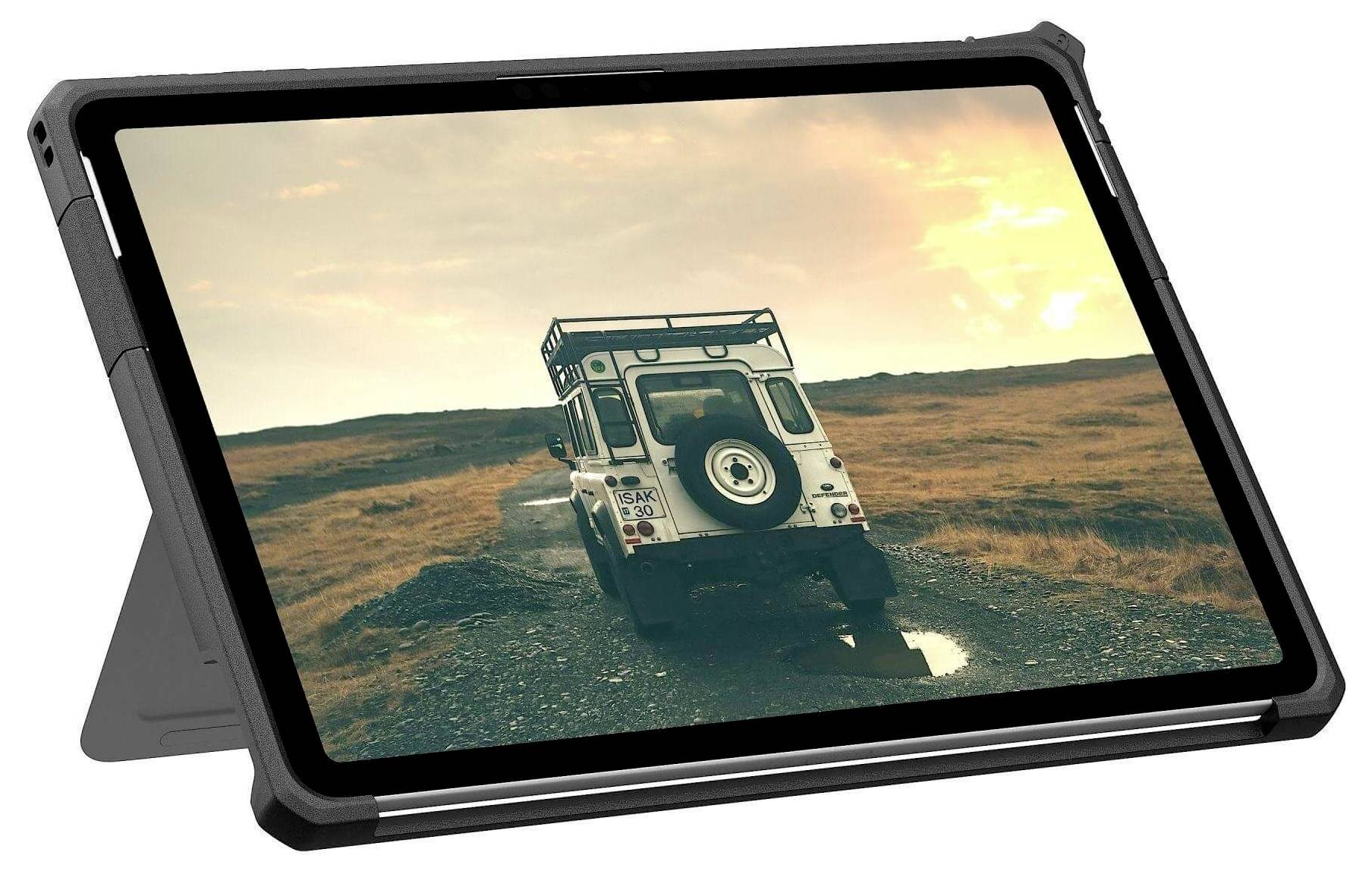 Ein Tablet, das ein Bild eines weißen Geländewagens auf einem Kiesweg zeigt, vor einem Sonnenuntergangshimmel über einer kargen Landschaft.