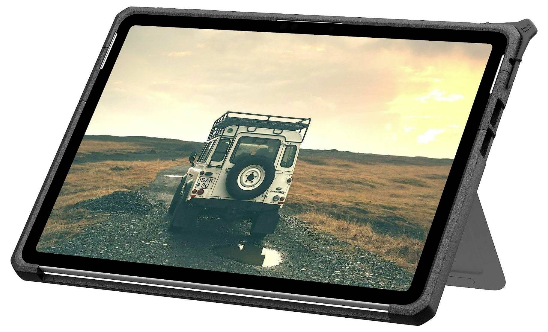 Ein Tablet, das ein Bild eines robusten Fahrzeugs auf einer Kiesstraße durch eine karge Landschaft bei Sonnenuntergang zeigt. Die Szene vermittelt ein Gefühl von Abenteuer und Erkundung.