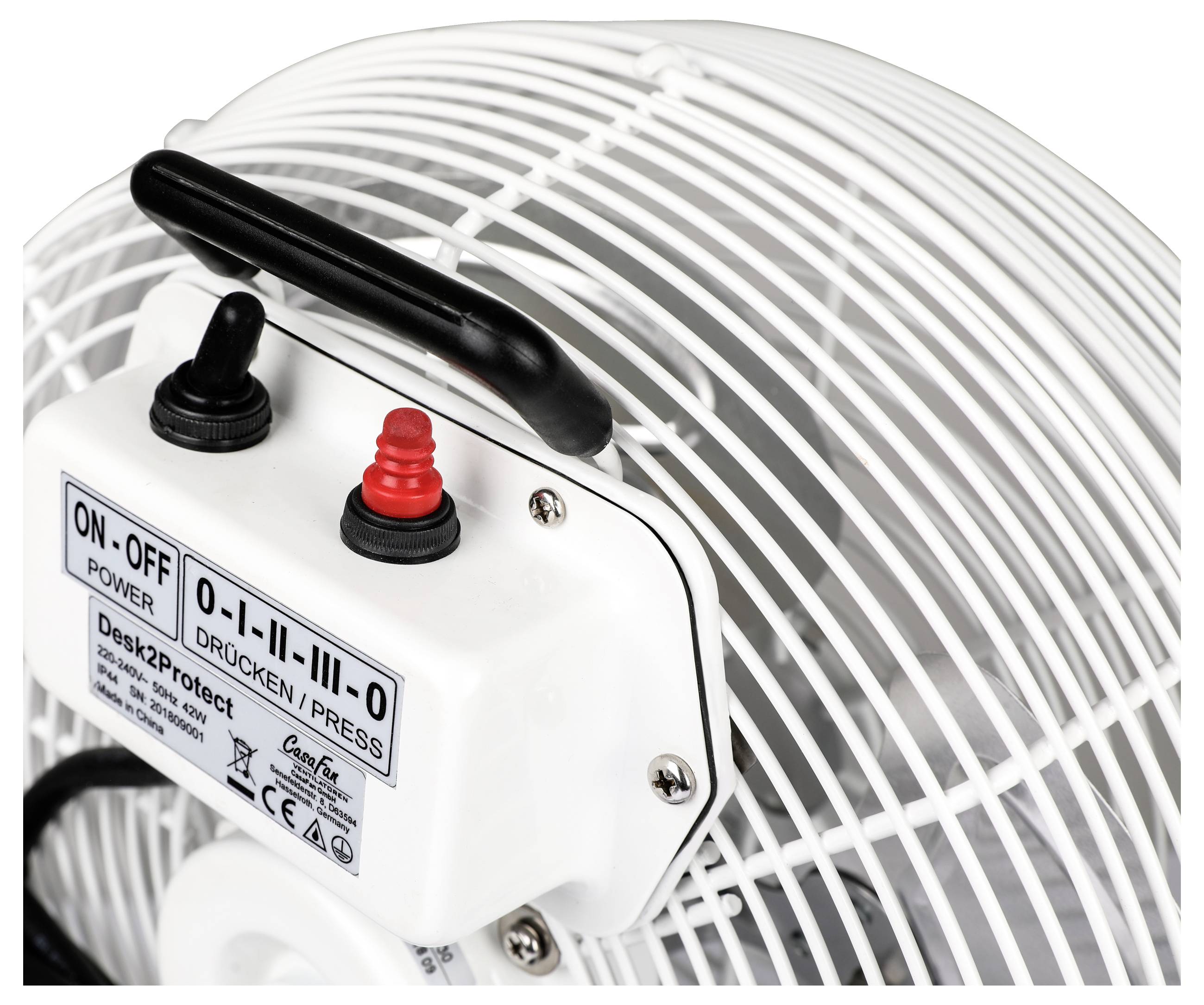 Nahaufnahme eines weißen Elektrolüfters mit einer Bedienungseinheit, die zwei Schalter für Ein/Aus und Druckeinstellung besitzt. Der Lüfter ist mit einem Schutzgitter versehen.