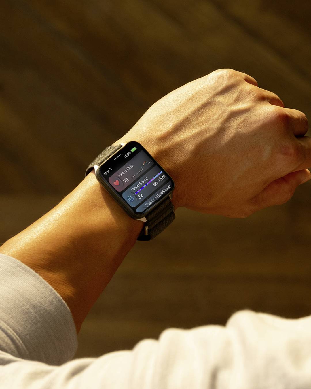 Eine Person trägt eine Smartwatch am Handgelenk, die Fitnessdaten wie Herzfrequenz, Schrittzahl und Uhrzeit anzeigt. Der Hintergrund ist unscharf.