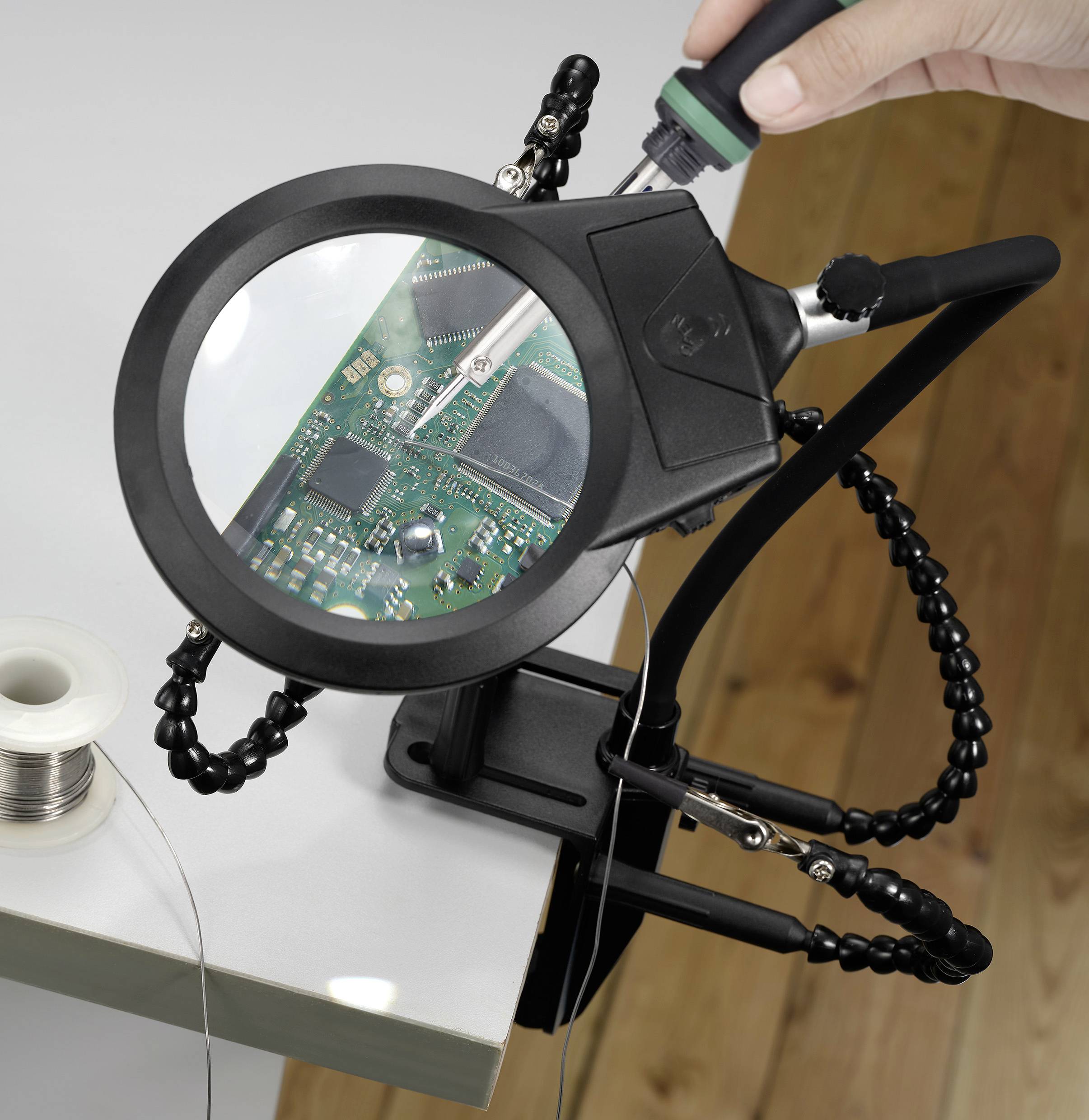 Eine Person verwendet ein Vergrößerungswerkzeug, um Komponenten auf einer grünen Leiterplatte zu löten, was Elektronik-Reparatur oder Montagearbeit andeutet.