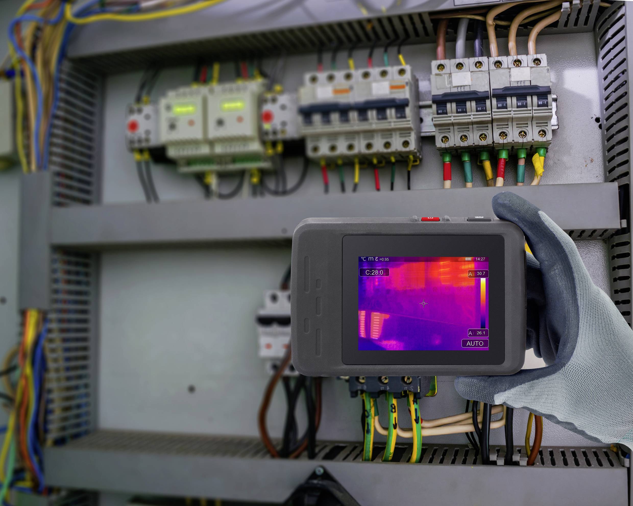 Eine Person verwendet eine Wärmekamera, um eine elektrische Schalttafel zu untersuchen und zeigt dabei Temperaturunterschiede für Wartungszwecke hervor.