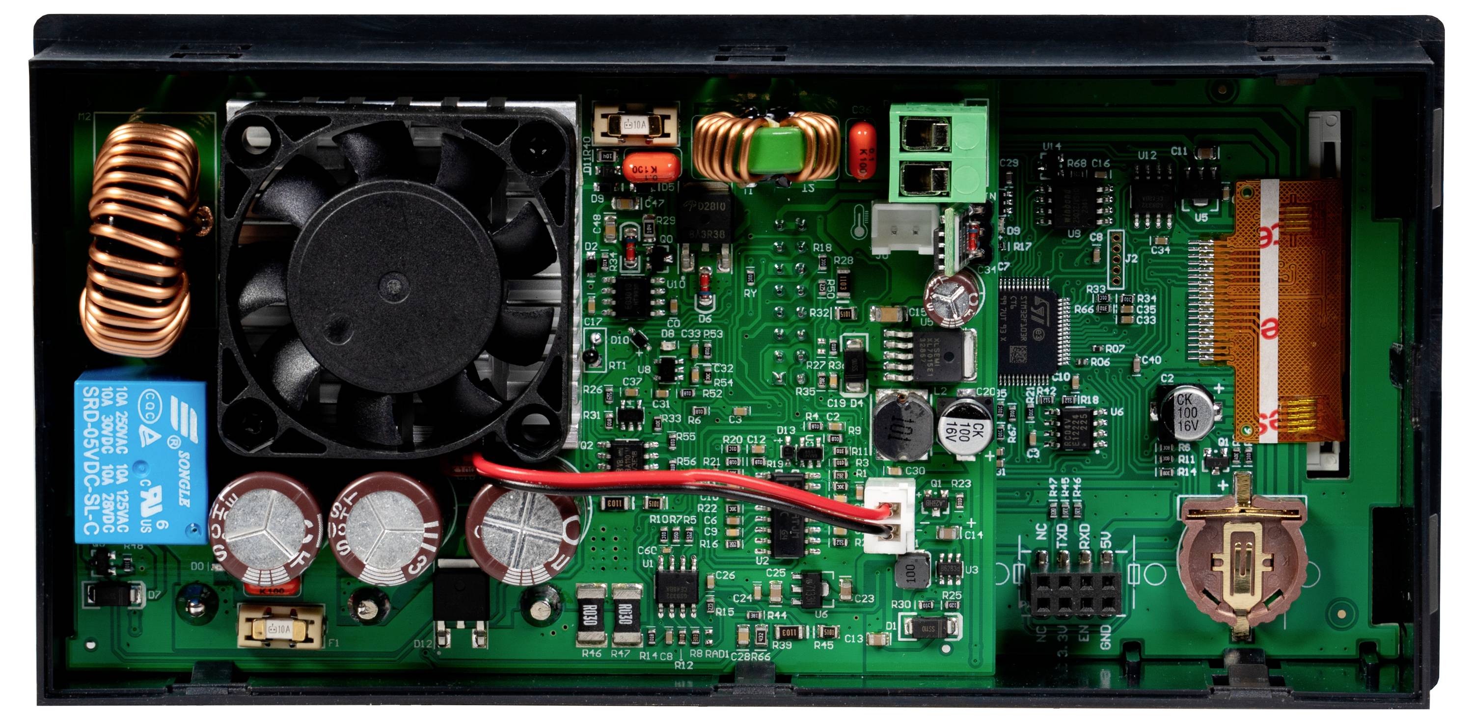 Eine offene elektronische Leiterplatte mit verschiedenen Komponenten, darunter Kondensatoren, Spulen, Anschlüsse und ein kleiner Kühlventilator.