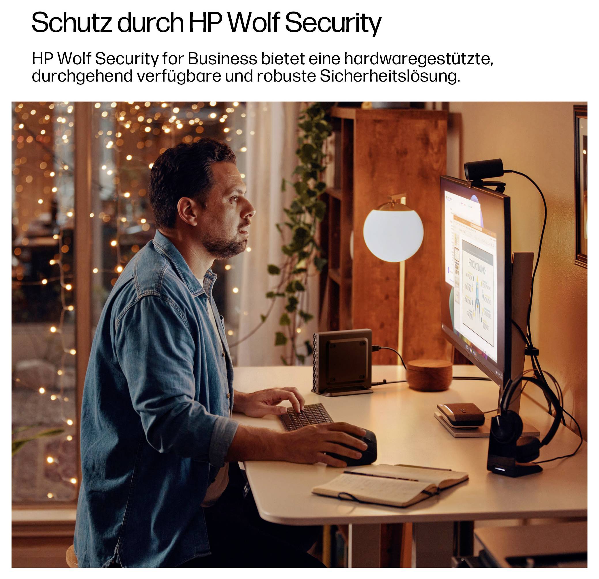 Eine Person sitzt an einem Schreibtisch und arbeitet an einem Computer, konzentriert auf einen Bildschirm, der Sicherheitssoftware zeigt. Die Umgebung ist ein häusliches Büro bei Nacht.