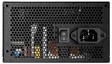 Nahaufnahme eines Computer-Netzteils, die einen Netzschalter, einen Anschlussport für Kabel und interne Komponenten hinter einem gelochten Gitter zeigt.