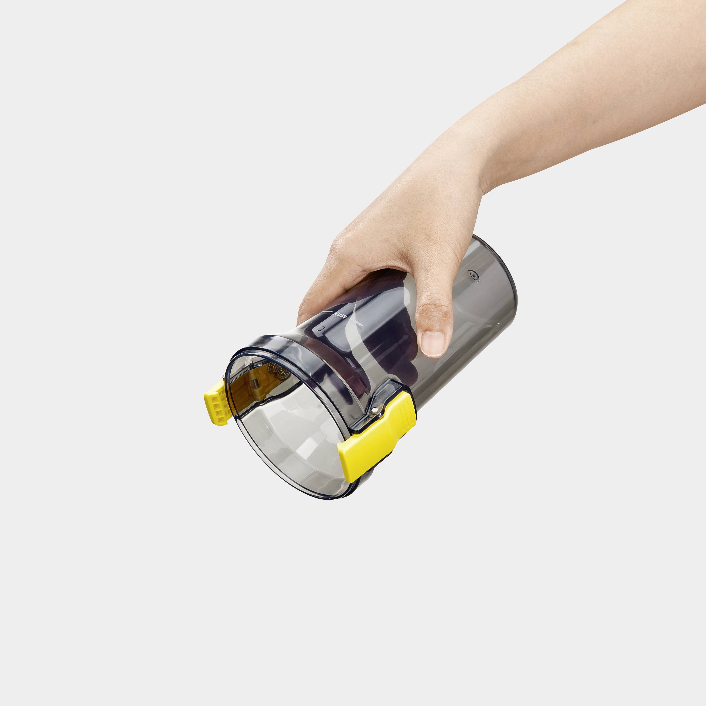 Eine Hand, die einen schwarzen Staubcontainer mit einem gelben Griff hält, leicht geneigt, wobei das tragbare Design und die Griffeigenschaft sichtbar sind.