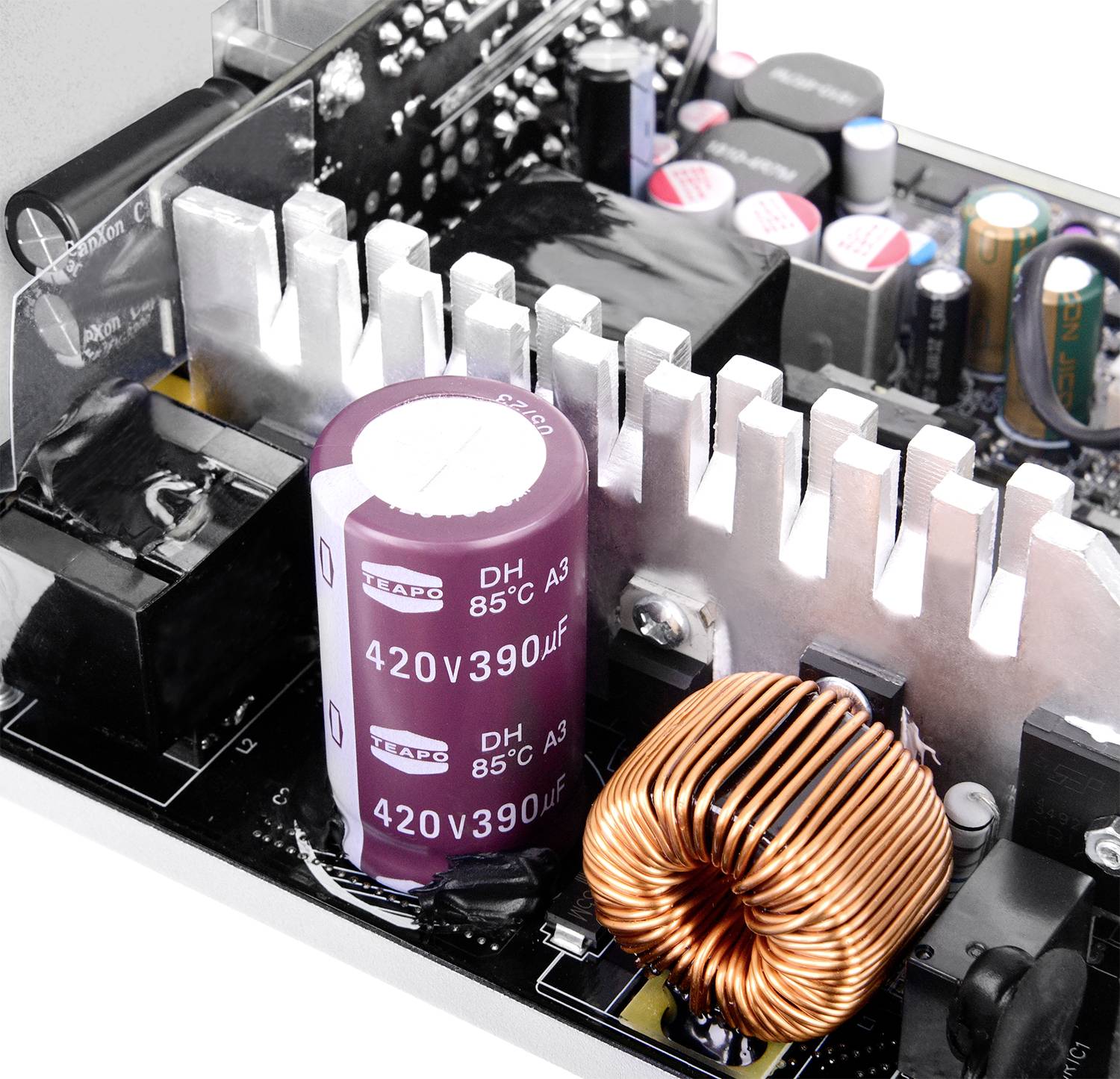 Nahaufnahme einer elektronischen Leiterplatte mit einem großen, violetten Kondensator, der mit '420V 390uF' gekennzeichnet ist, einer Kupferspule und Kühlkörperlamellen.