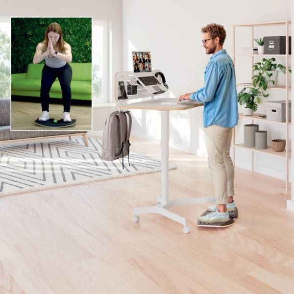 Eine Person steht an einem Schreibtisch auf einem Balancebrett und arbeitet an einem Laptop. Eine Einblendung zeigt eine weitere Person, die auf einem anderen Balancebrett hockt.