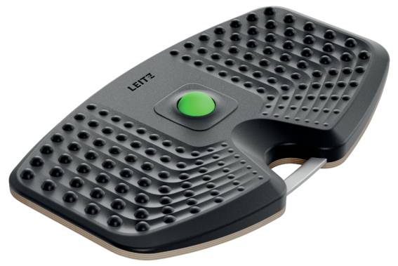 Ein schwarzer, ergonomischer Fußstütze mit einer strukturierten Oberfläche und einem zentralen grünen Knopf, entwickelt zur Verbesserung von Komfort und Körperhaltung am Schreibtisch.