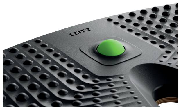 Ein strukturiertes schwarzes Gerät mit einer auffälligen grünen Taste in der Mitte, mit der Aufschrift 