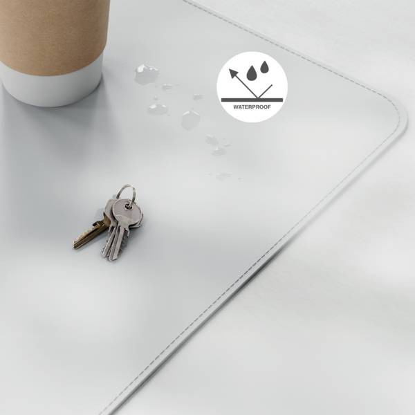 Eine braune Papiertasse und Schlüssel ruhen auf einer wasserdichten weißen Oberfläche, mit einem Wassertropfen-Symbol, das Schutz vor Verschüttungen anzeigt.