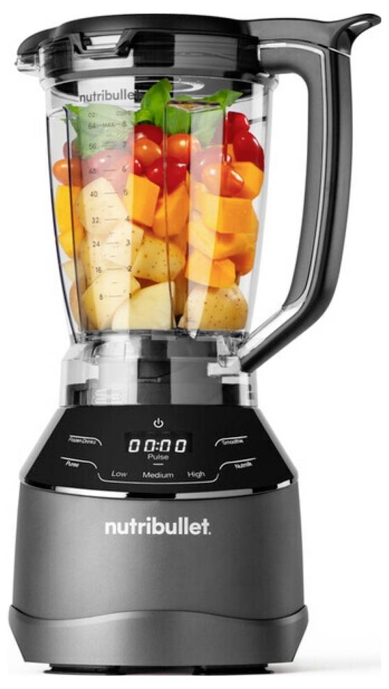 Ein hoher, dunkelgrauer Nutribullet-Mixer, gefüllt mit verschiedenen Obst- und Gemüsesorten, darunter Kirschtomaten, Karotten und Orangenscheiben.