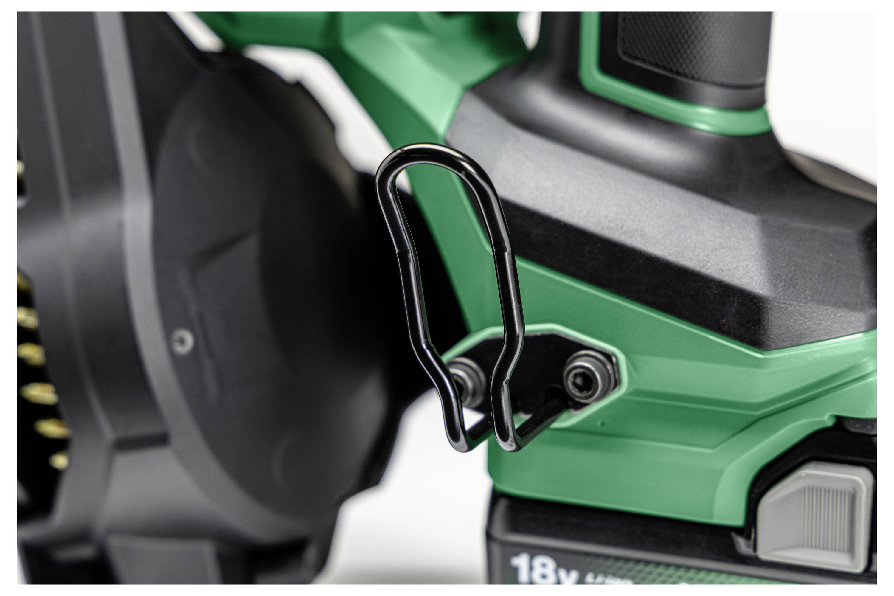 Eine Nahaufnahme eines grünen und schwarzen Werkzeugs mit einem sichtbaren schwarzen Haken und einer Batterie mit der Aufschrift „18V