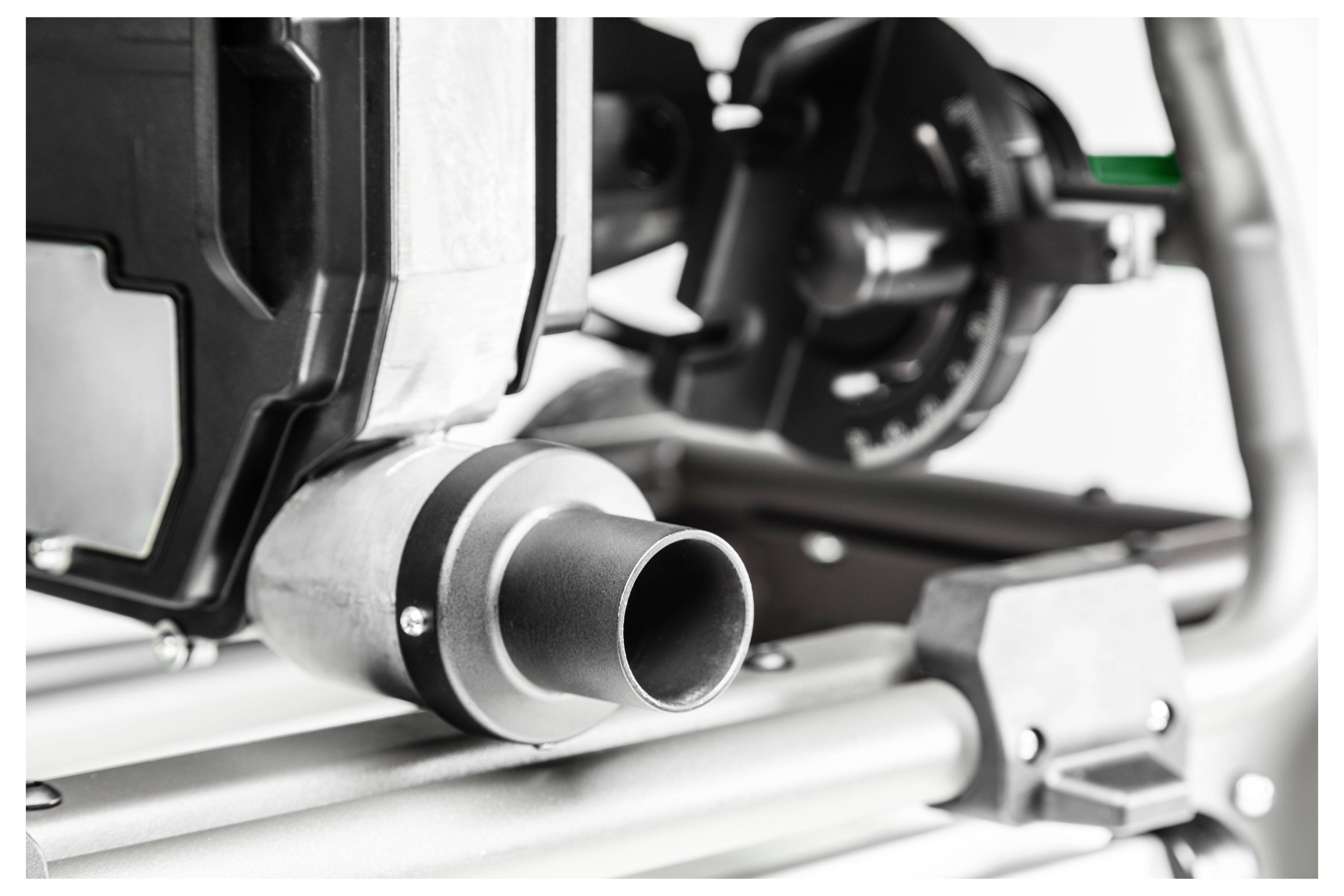 Eine Nahaufnahme von industrieller Ausrüstung, die sich auf ein Rohr konzentriert, das mit einer großen Maschinenkomponente verbunden ist, wobei Schrauben und Metallrahmen sichtbar sind.