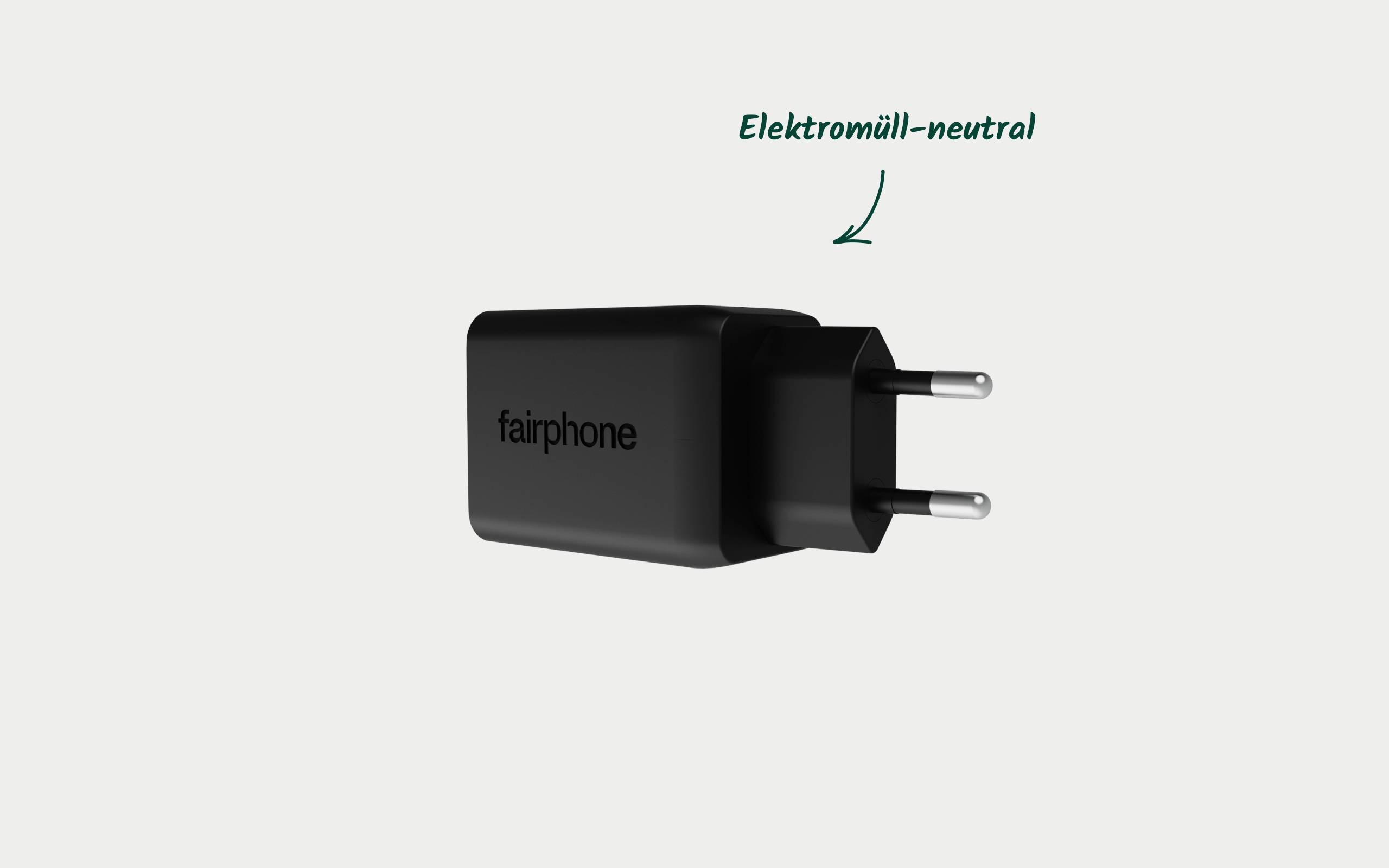 Schwarzes Ladegerät von Fairphone mit europäischem Stecker. Text: 'Elektromüll-neutral', was auf Umweltfreundlichkeit hinweist.