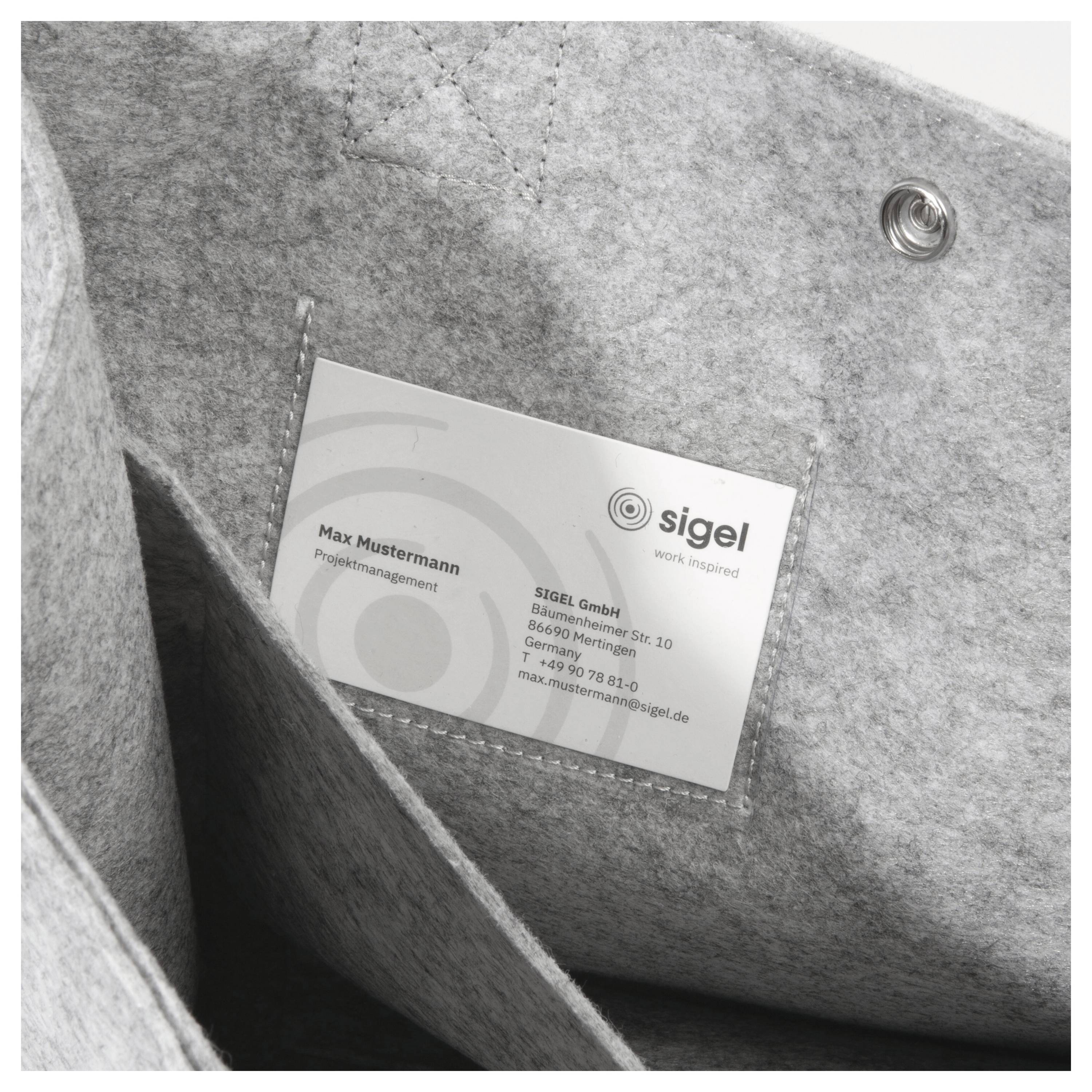 Eine Visitenkarte, eingelegt in einem grauen Filzhalter. Die Karte enthält den Namen 'Max Mustermann', die Position 'Projektmanagement' und Firmendetails.