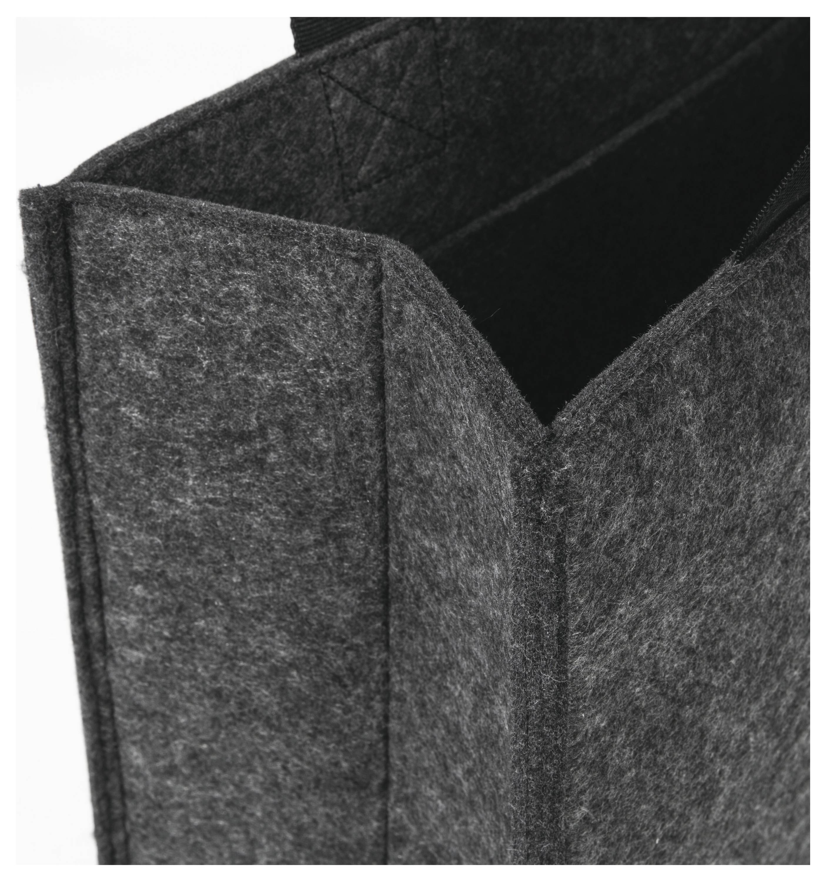 Eine Nahaufnahme einer grauen Filztasche, die deren strukturierte Oberfläche und robuste Nähte zeigt. Der offene Taschentop gibt einen geräumigen Innenraum preis.