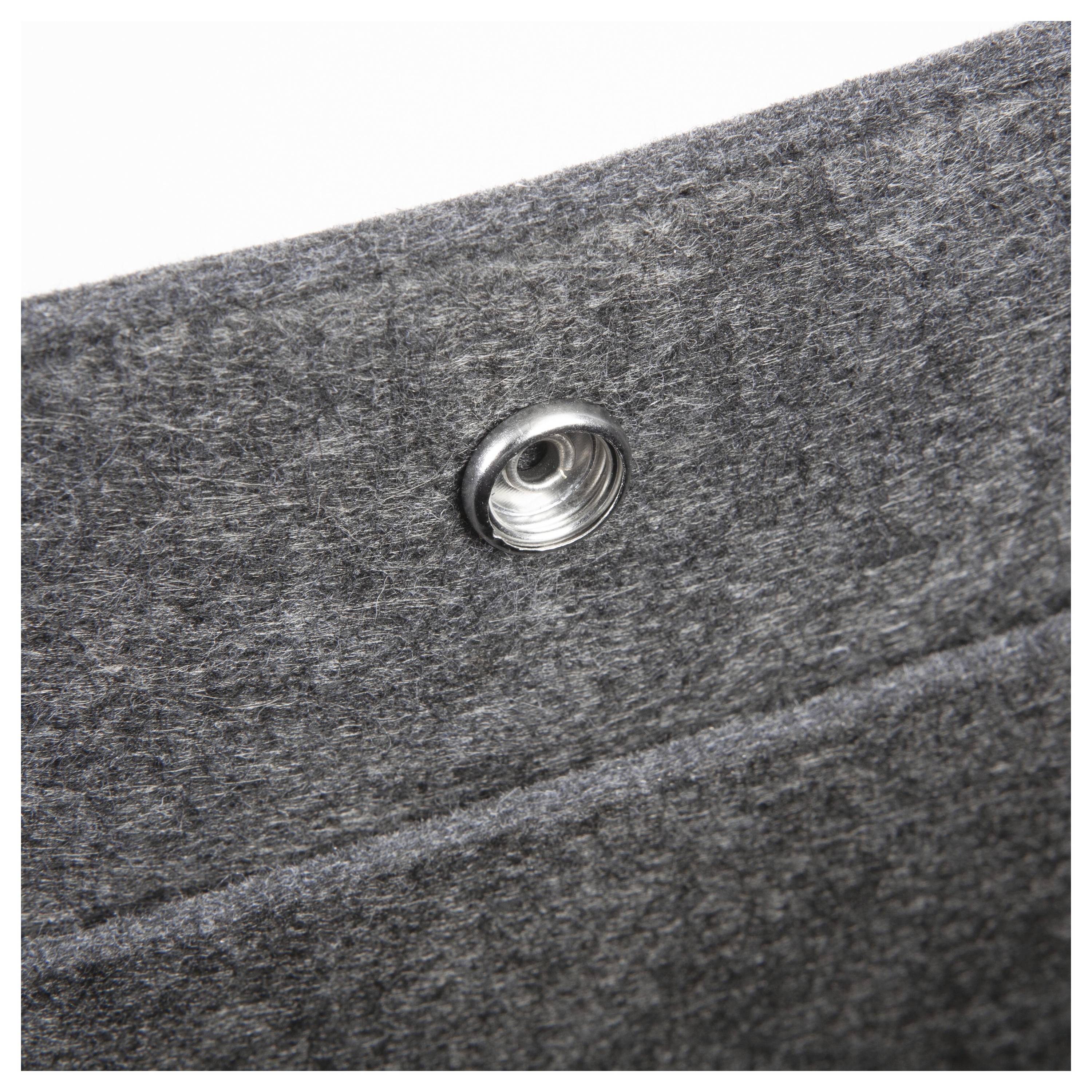 Eine Nahaufnahme eines grauen Filzmaterials mit einer kreisförmigen Metallöse, die die Textur und Details des Gewebes und der Beschläge hervorhebt.