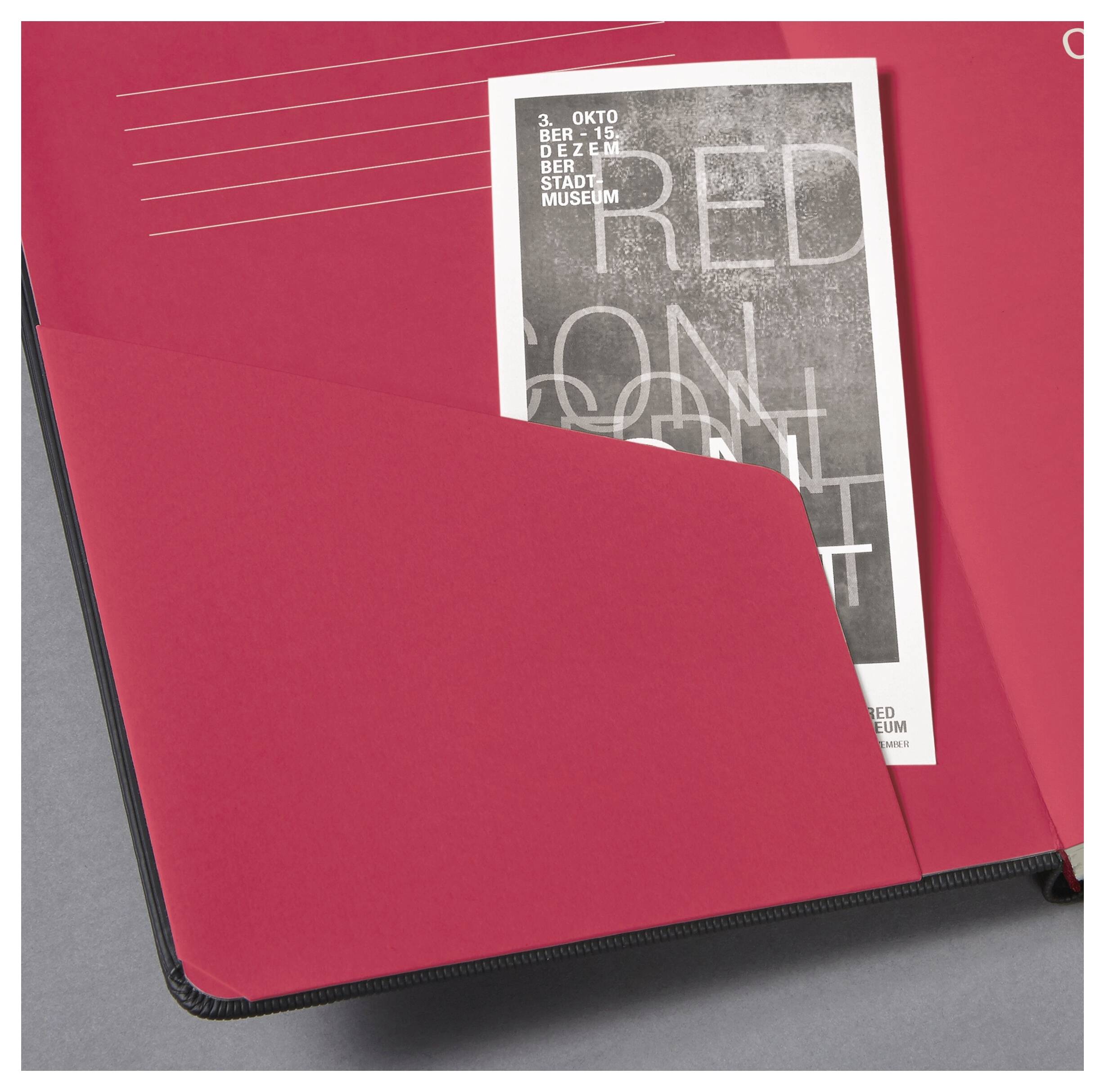 Ein schwarzes Notizbuch mit einer roten Innenseite, das eine Broschüre enthält, auf der 