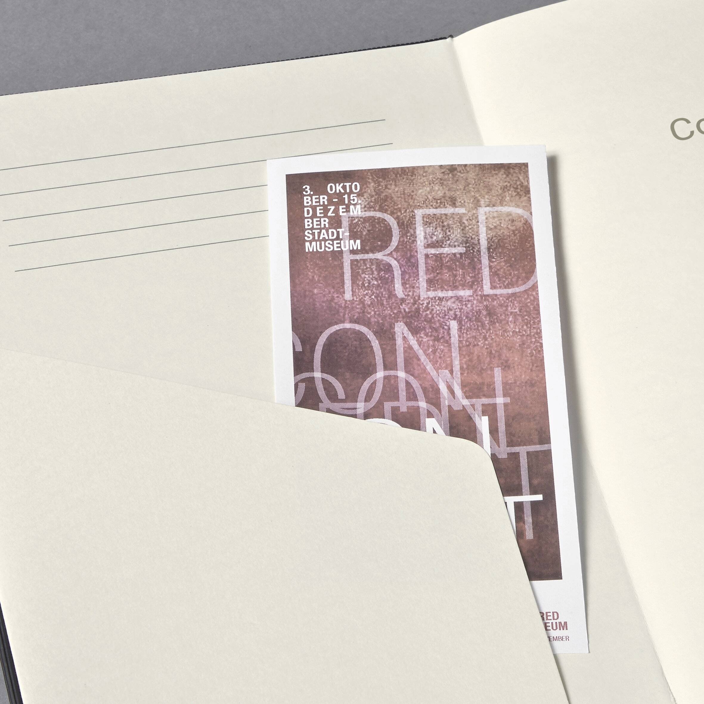 Eine Postkarte, die teilweise in einen Umschlag geschoben ist, zeigt eine strukturierte Textüberlagerung in rosafarbenen Tönen, wobei 'Museum' und die Datumsangaben 'Okt - Dez' sichtbar sind.