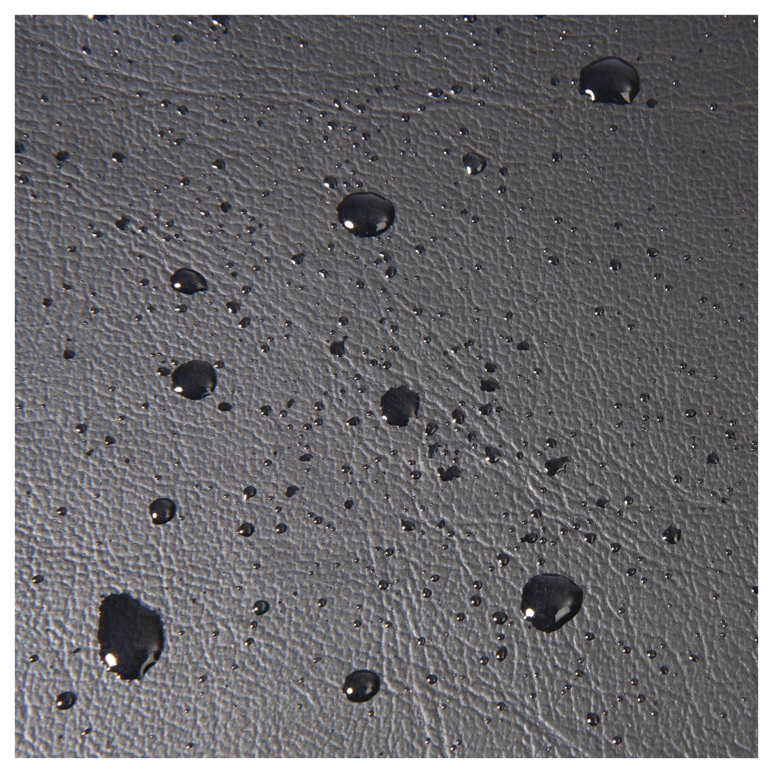 Wassertropfen auf einer strukturierten schwarzen Oberfläche, die ein Muster erzeugen und die Textur des Materials hervorheben.