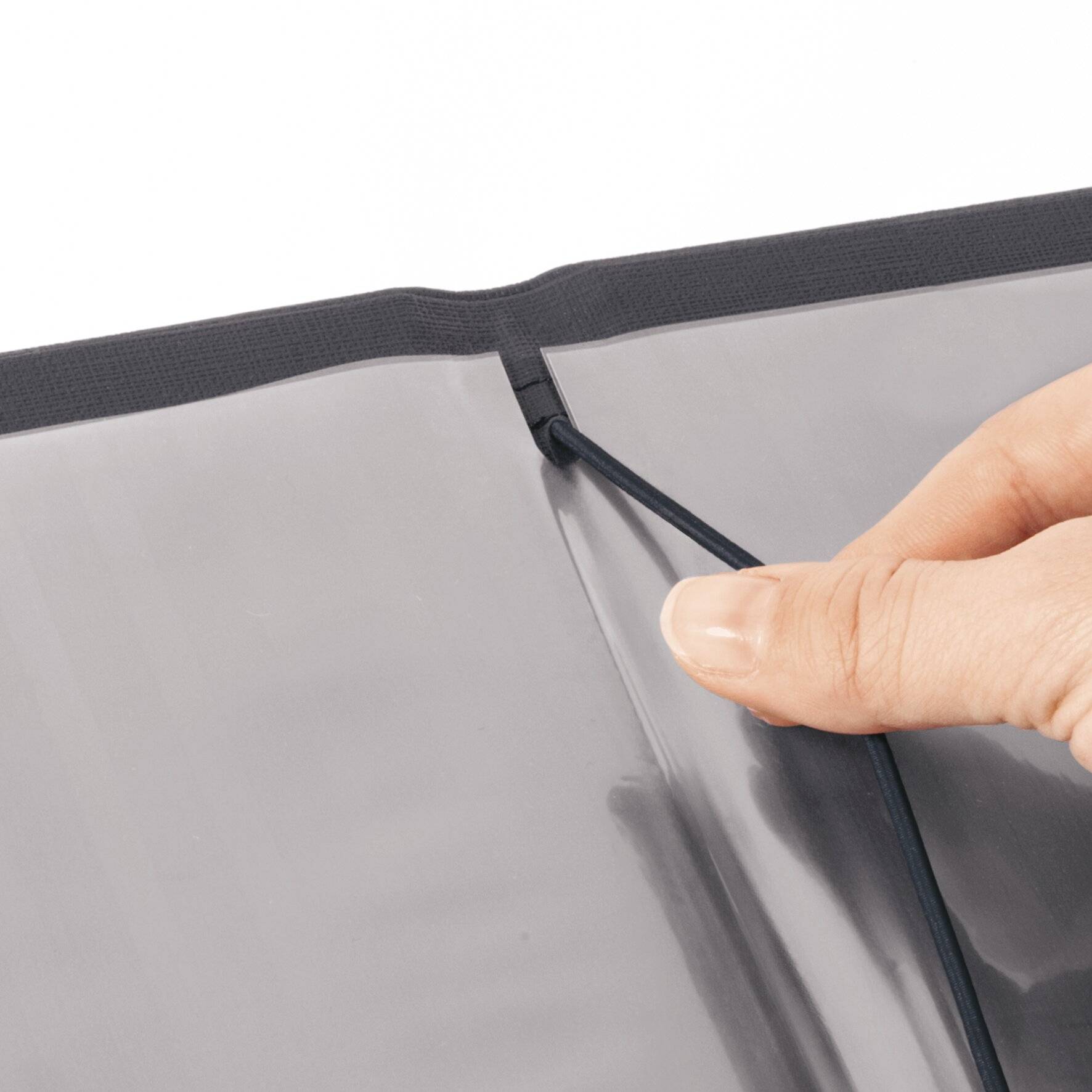 Hand öffnet einen schwarzen Ordner und enthüllt eine transparente Innentasche.