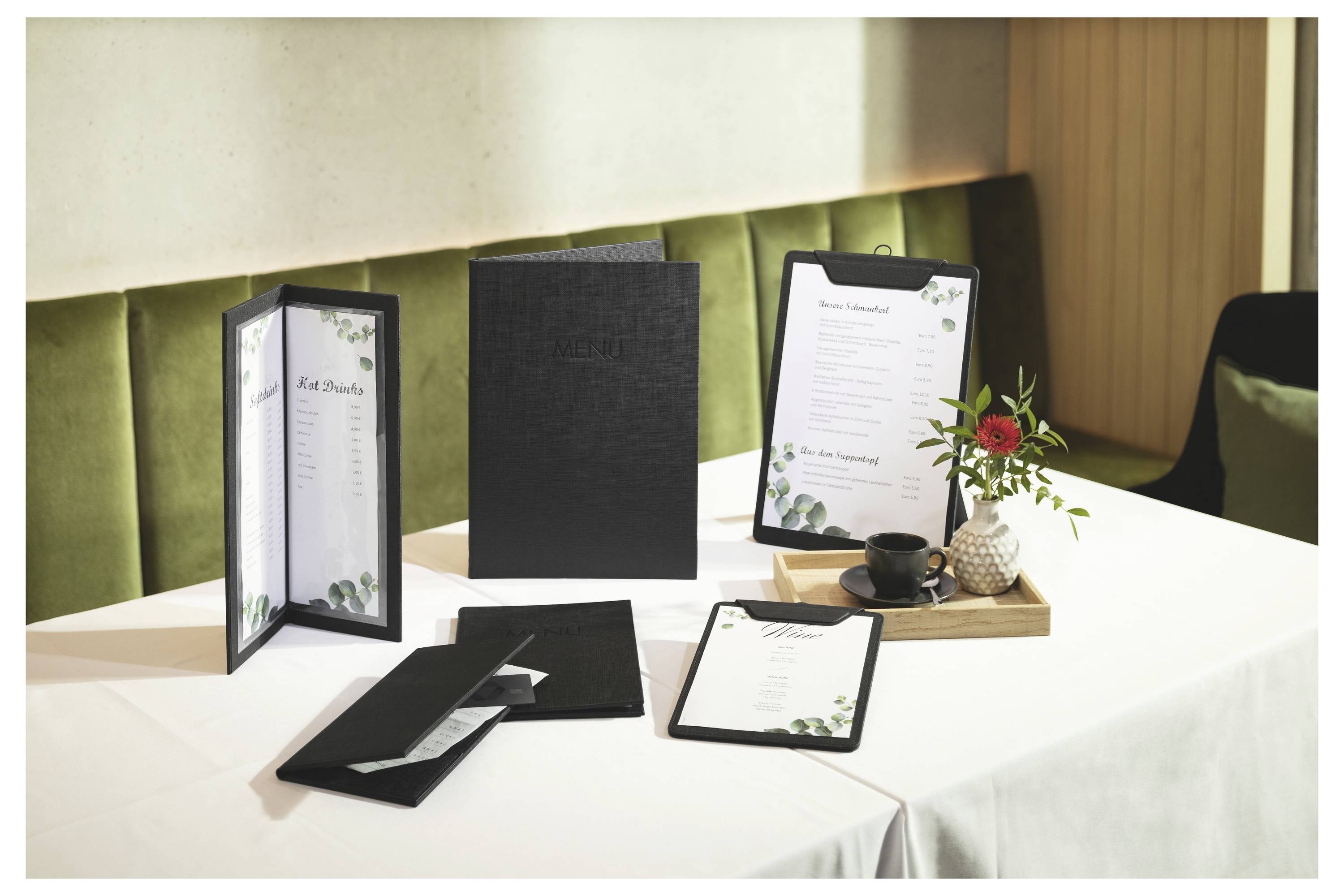 Elegante Schwarzweiß-Menü- und Einladungskollektion auf einem weißen Tisch angezeigt, mit Blumenakzenten und einer kleinen Tasse in einer formellen Veranstaltungskulisse.