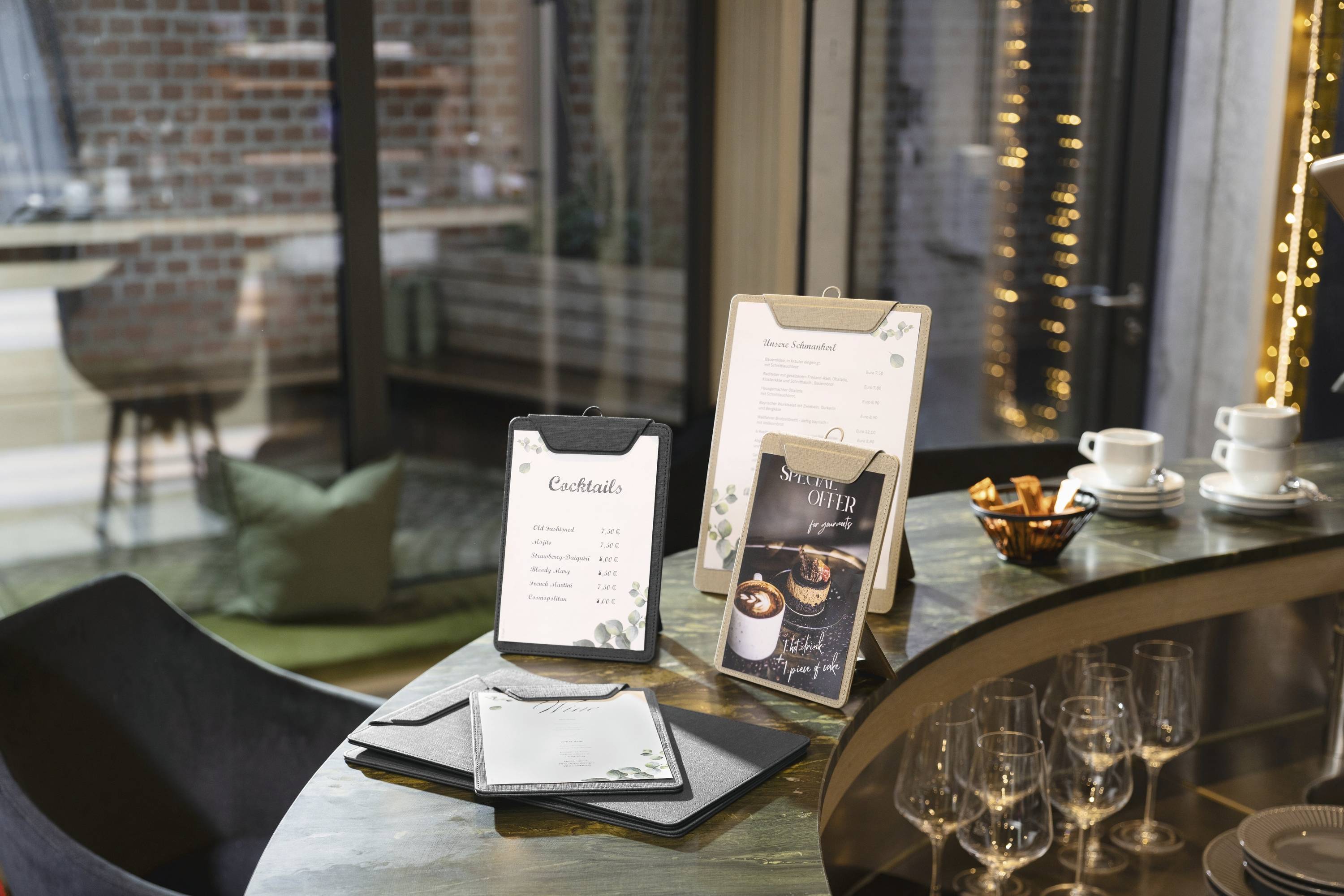 Eine gemütliche Bar-Atmosphäre mit Cocktailkarte auf dem Tisch. Inklusive Kaffee-Schild und elegantem Gläserservice, mit gedämpftem Licht und modernem Design.