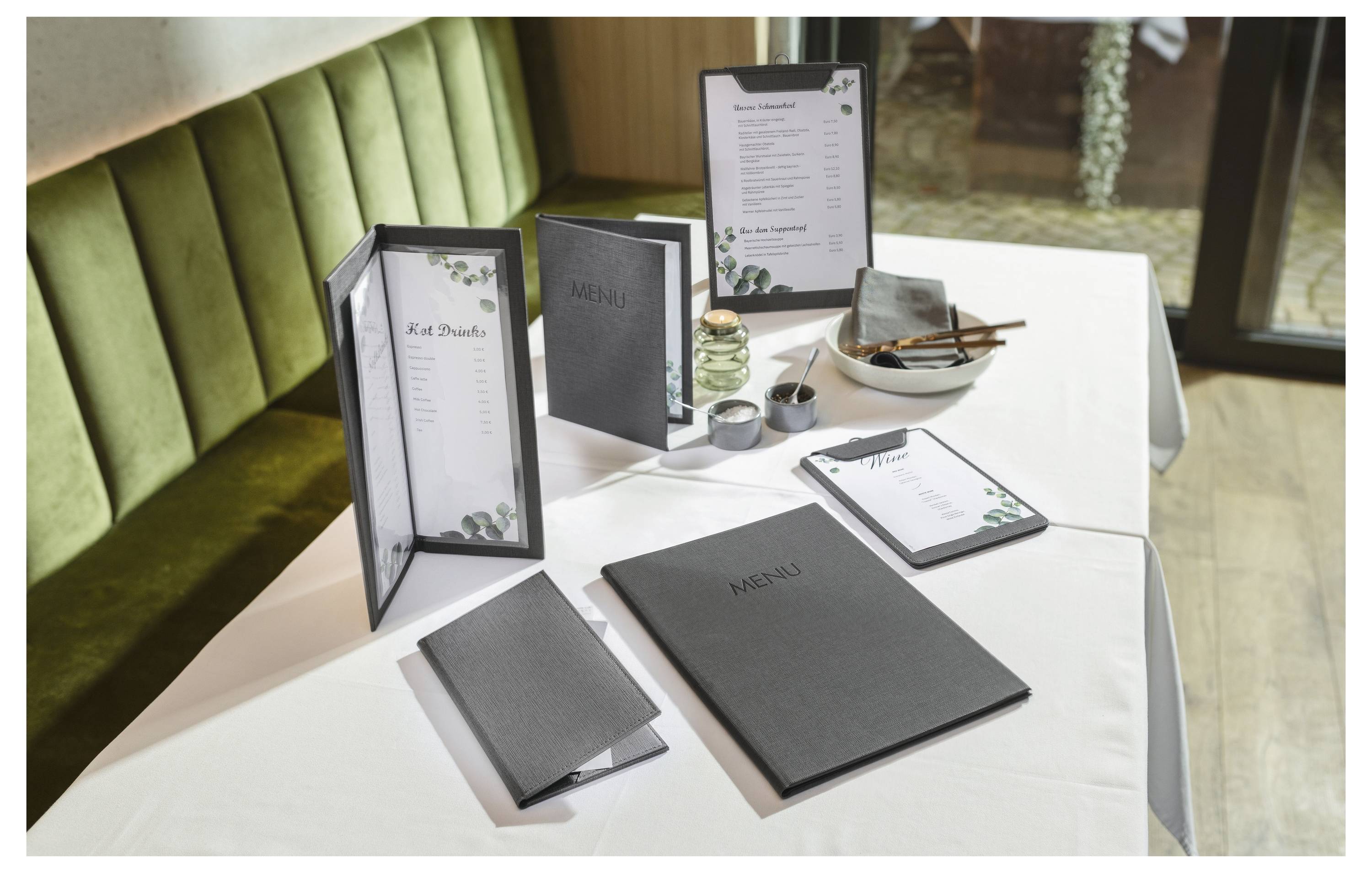 Restauranttisch mit schwarzweißen Speisekarten, einer Klemmbrett und Würzmitteln auf einem weißtischdeckten Boxensitz.