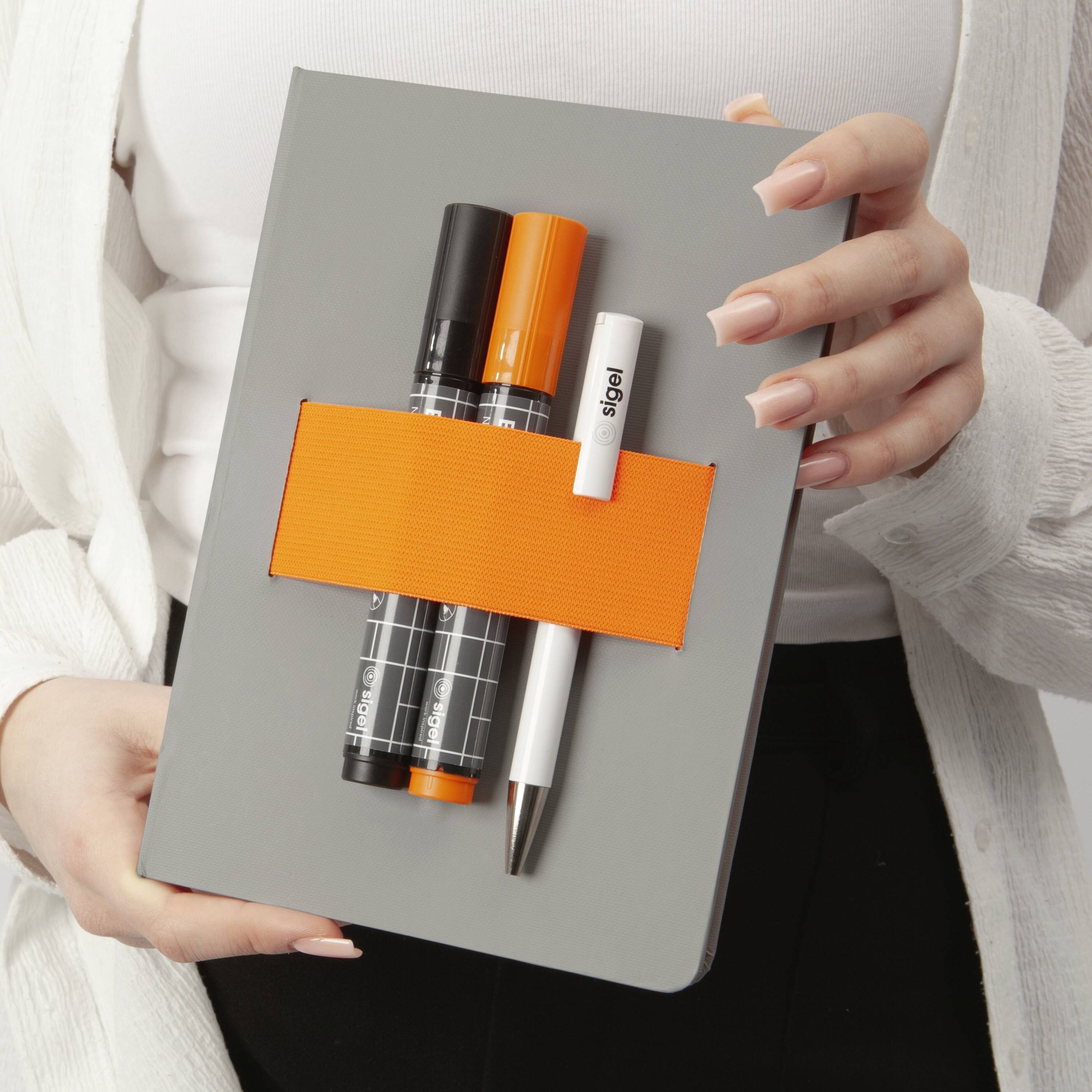 Eine Person, die eine graue Box mit einem leuchtend orangefarbenen Band hält, in der sich zwei Marker und ein weißer Stift befinden. Der Oberkörper der Person ist teilweise sichtbar.