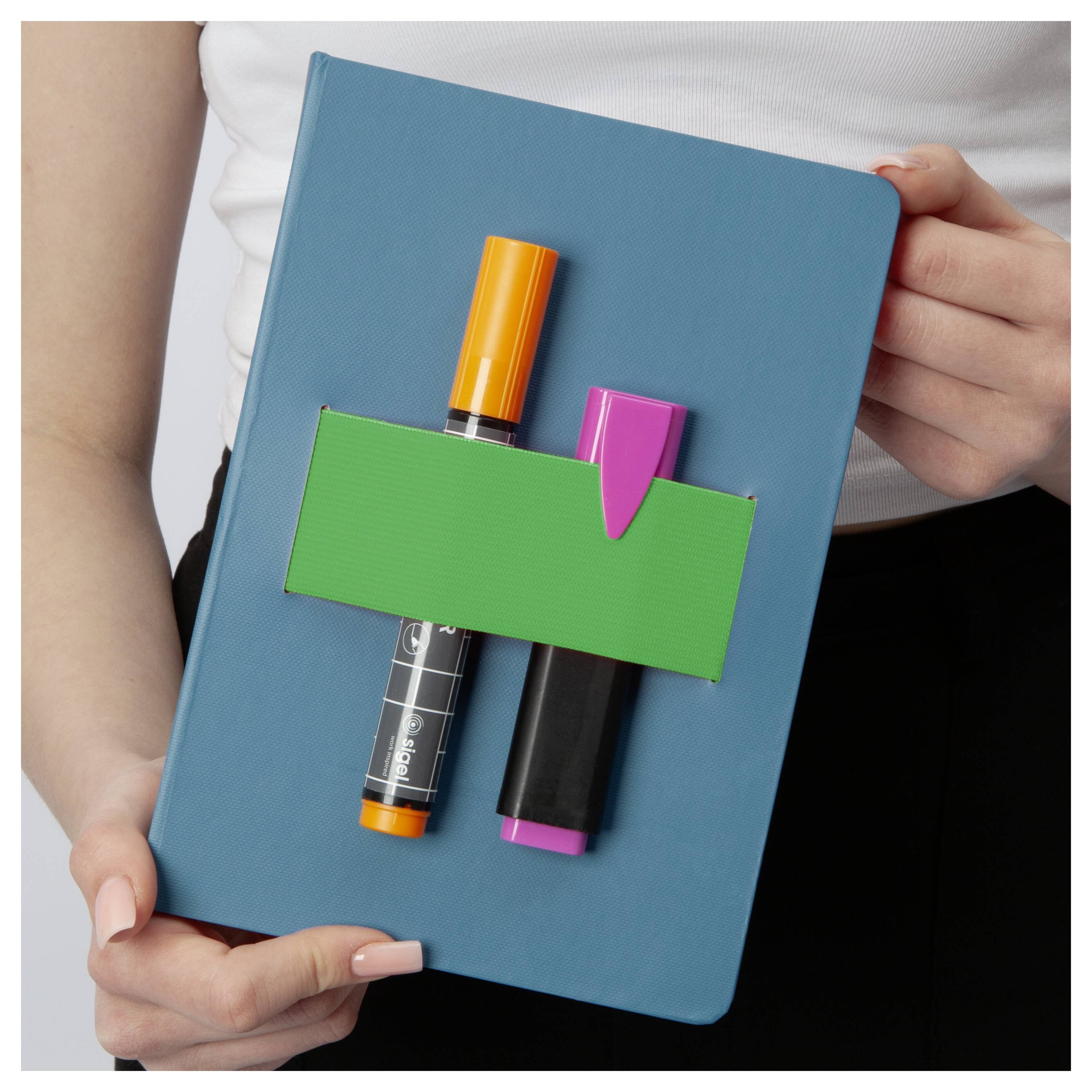 Person mit einem blauen Notizbuch mit einer grünen Tasche und zwei Markern, die an der Vorderseite befestigt sind.