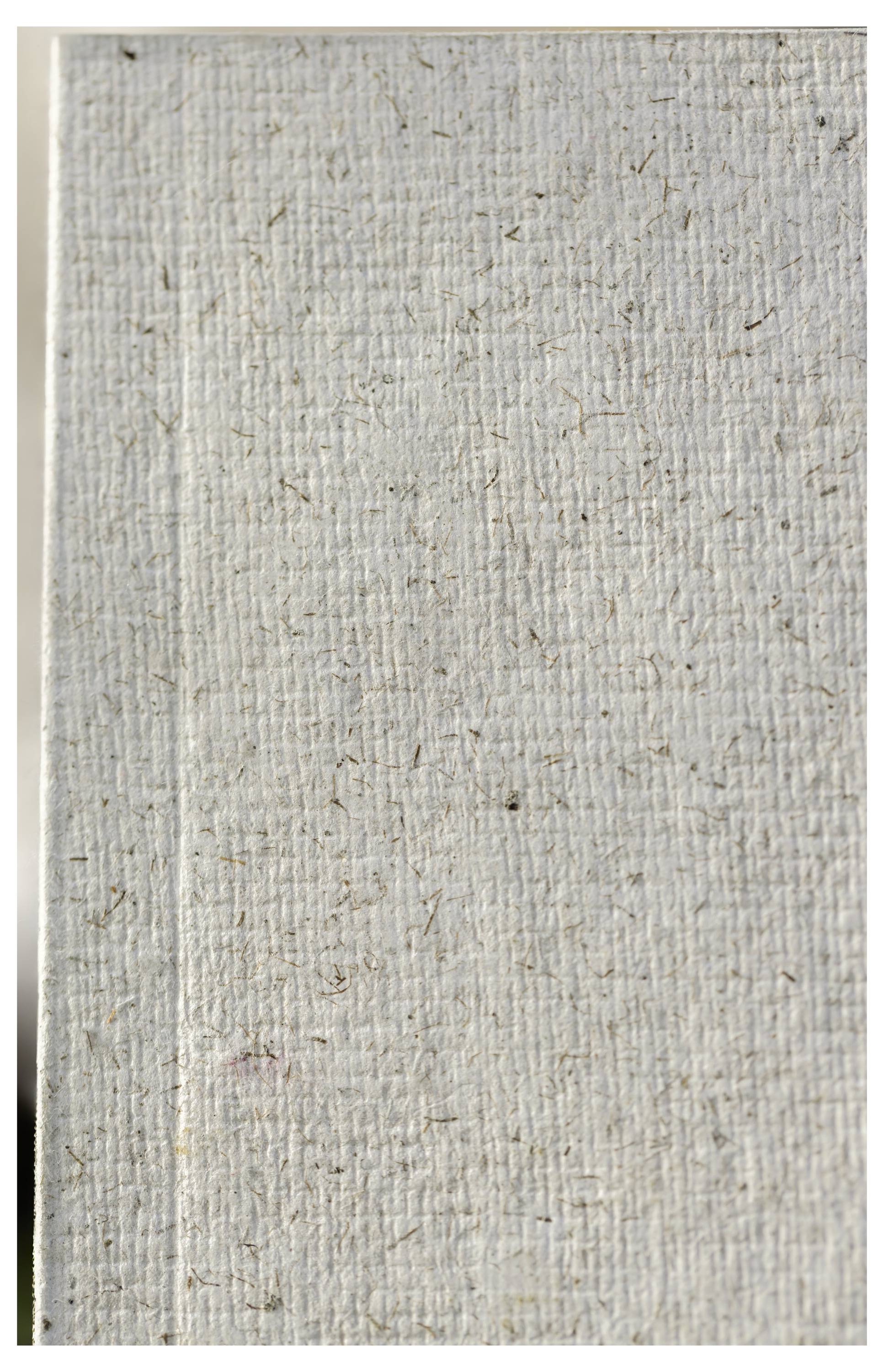 Nahaufnahme einer leeren, cremefarbenen strukturierten Leinwand- oder Papierfläche mit einer sichtbaren gefalteten Kante auf der linken Seite.