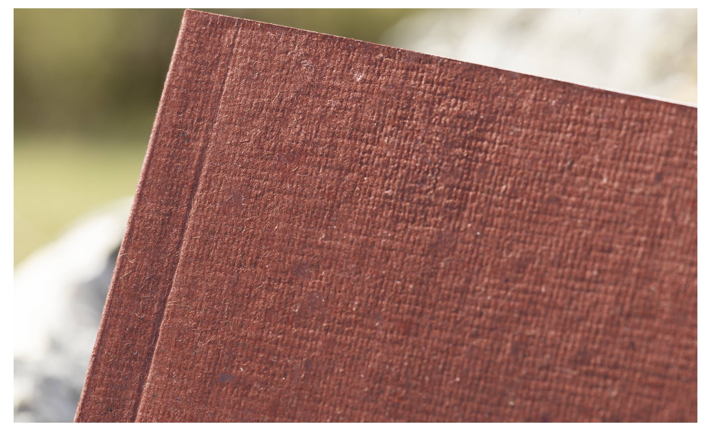 Nahaufnahme einer roten strukturierten Hardcover-Buchkante vor unscharfem Hintergrund
