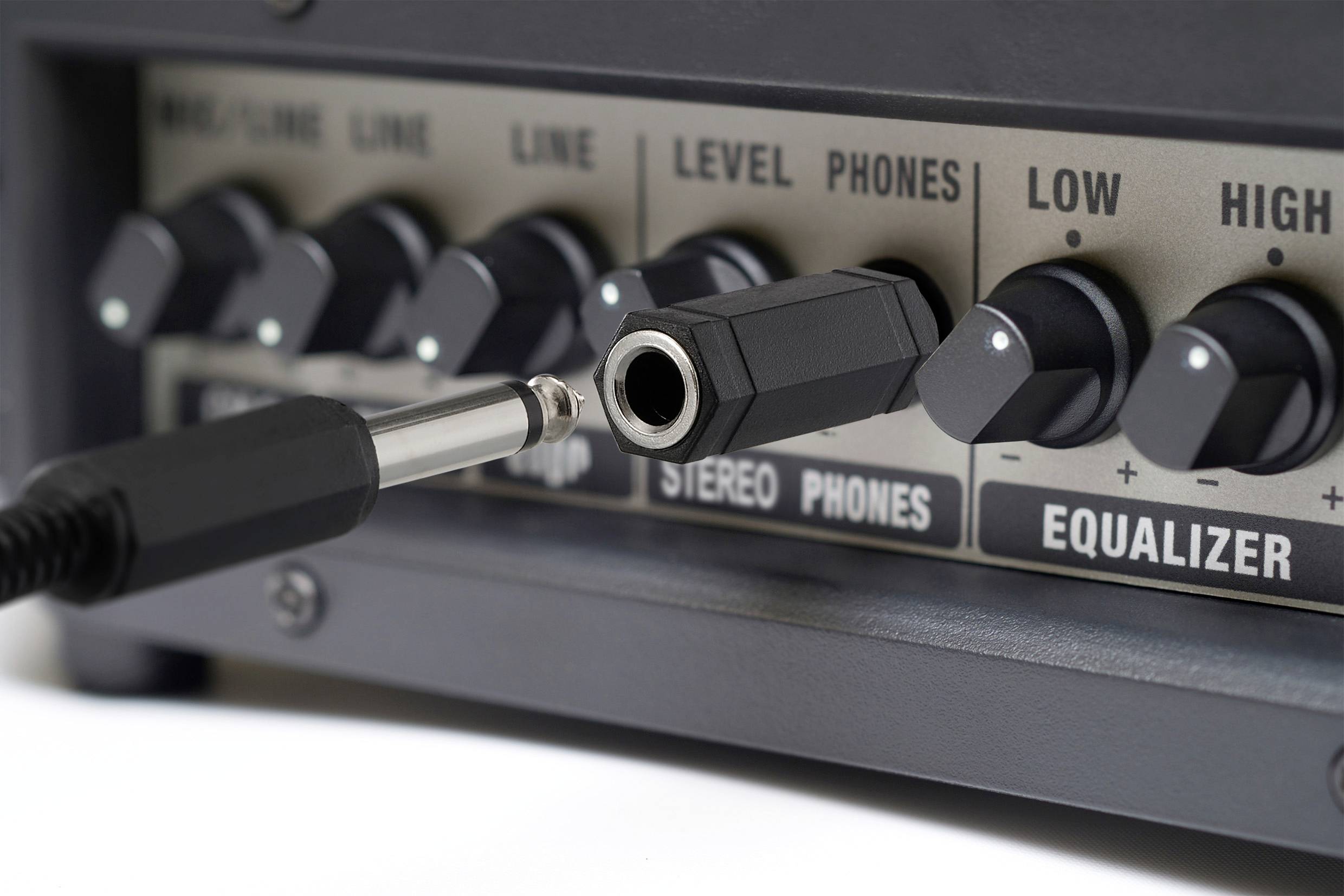 Eine Nahaufnahme von Audioausrüstung zeigt mehrere Regler und einen nicht angeschlossenen Audioanschluss. Beschriftungen umfassen 