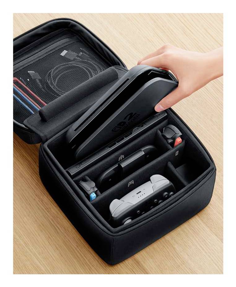 Eine Hand legt eine Spielkonsole in einen gepolsterten Aufbewahrungskoffer, der auch zwei Controller und verschiedene Kabel in Fächern enthält.