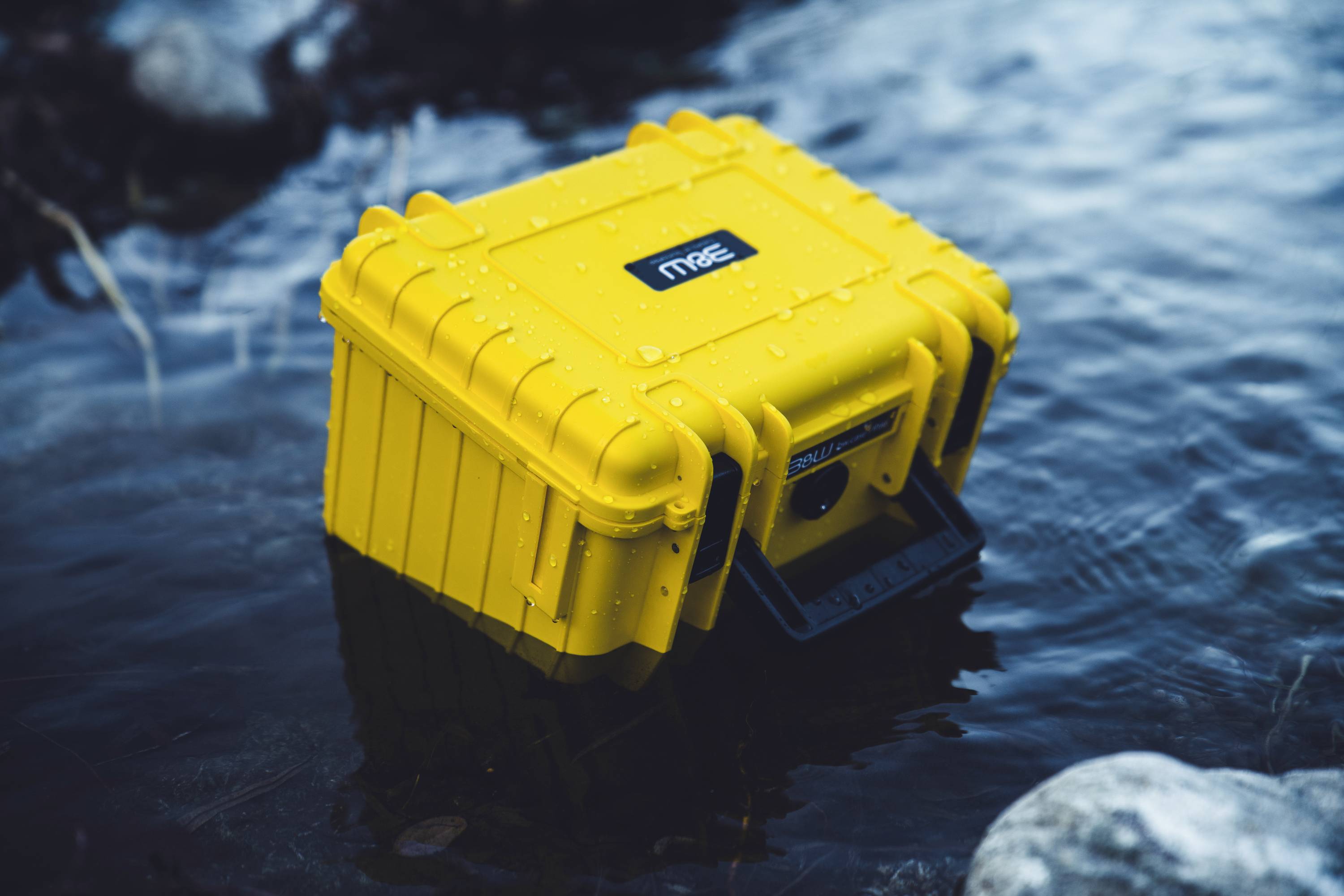 Ein gelber wasserdichter Koffer, der in einem Gewässer schwimmt und seine Robustheit und Wasserdichtigkeit demonstriert.