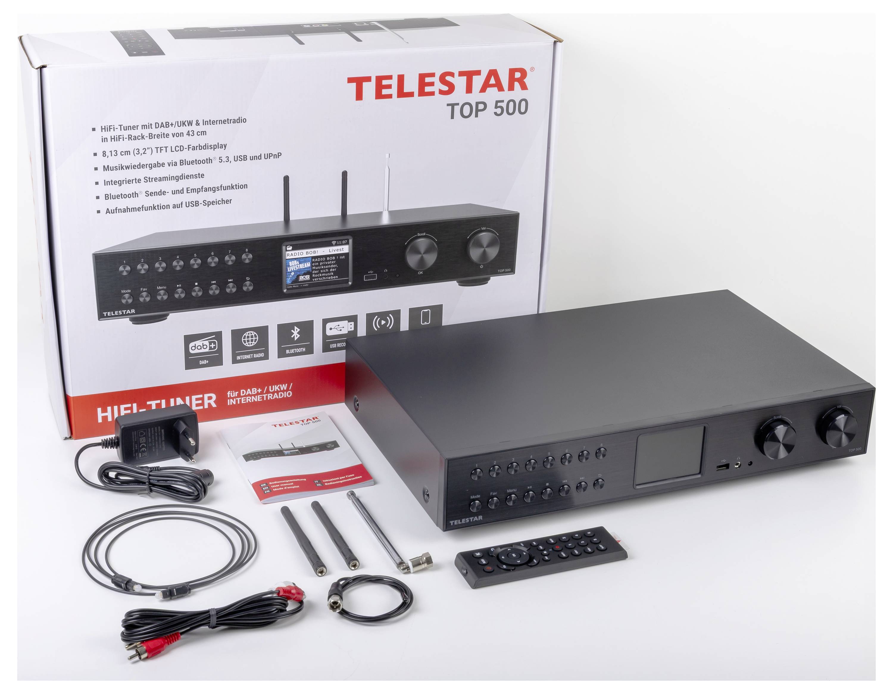 Ein Telestar Top 500 Digitalradioempfänger mit Fernbedienung, Kabeln und Antennen wird neben seiner Verpackung präsentiert, auf der Funktionen in mehreren Sprachen aufgeführt sind.