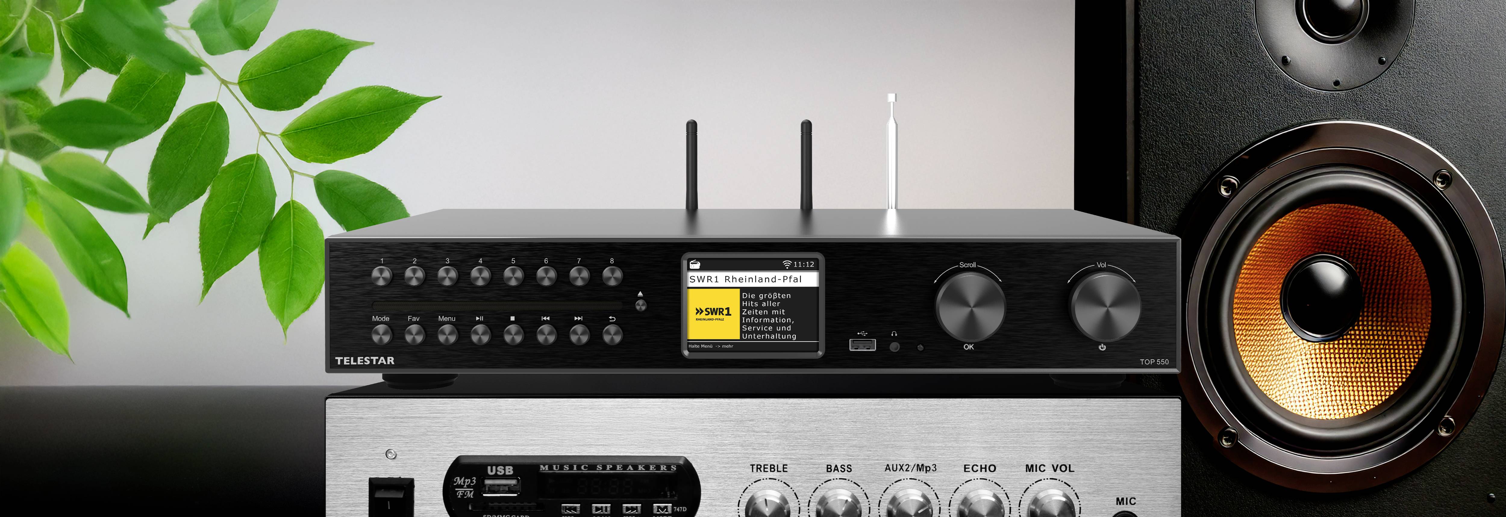 Ein schwarzer Audioempfänger mit zwei Antennen und verschiedenen Bedienelementen wird auf einem silbernen Verstärker platziert, neben einem großen Lautsprecher.