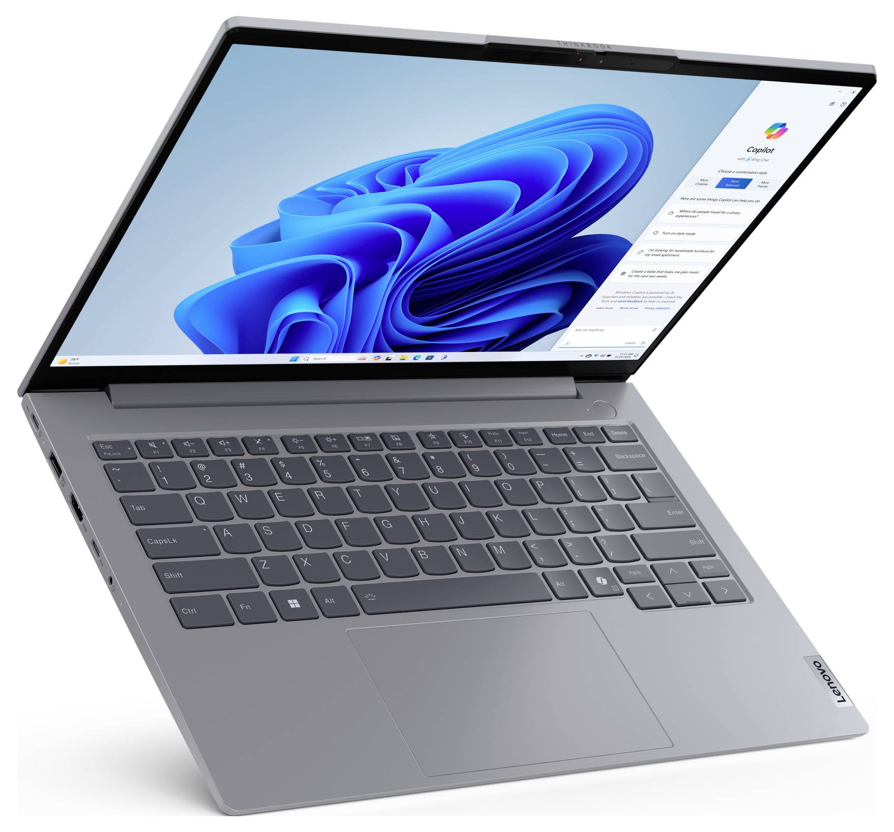 Ein silberner Laptop, teilweise geöffnet, zeigt einen Windows 11 Bildschirm mit Widgets und Apps. Die Tastatur und das Trackpad sind sichtbar.