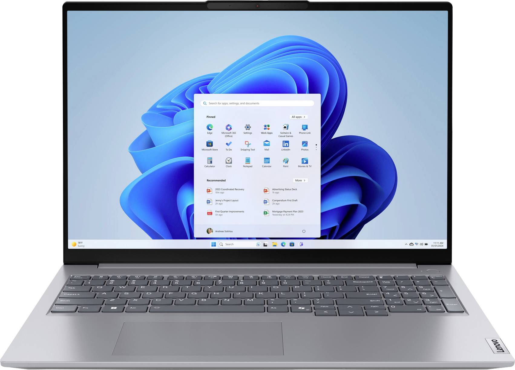 Ein Laptop mit silbernem Gehäuse und einem Bildschirm, auf dem das Windows 11 Startmenü angezeigt wird, vor einem blauen abstrakten Wirbeldesign im Hintergrund.