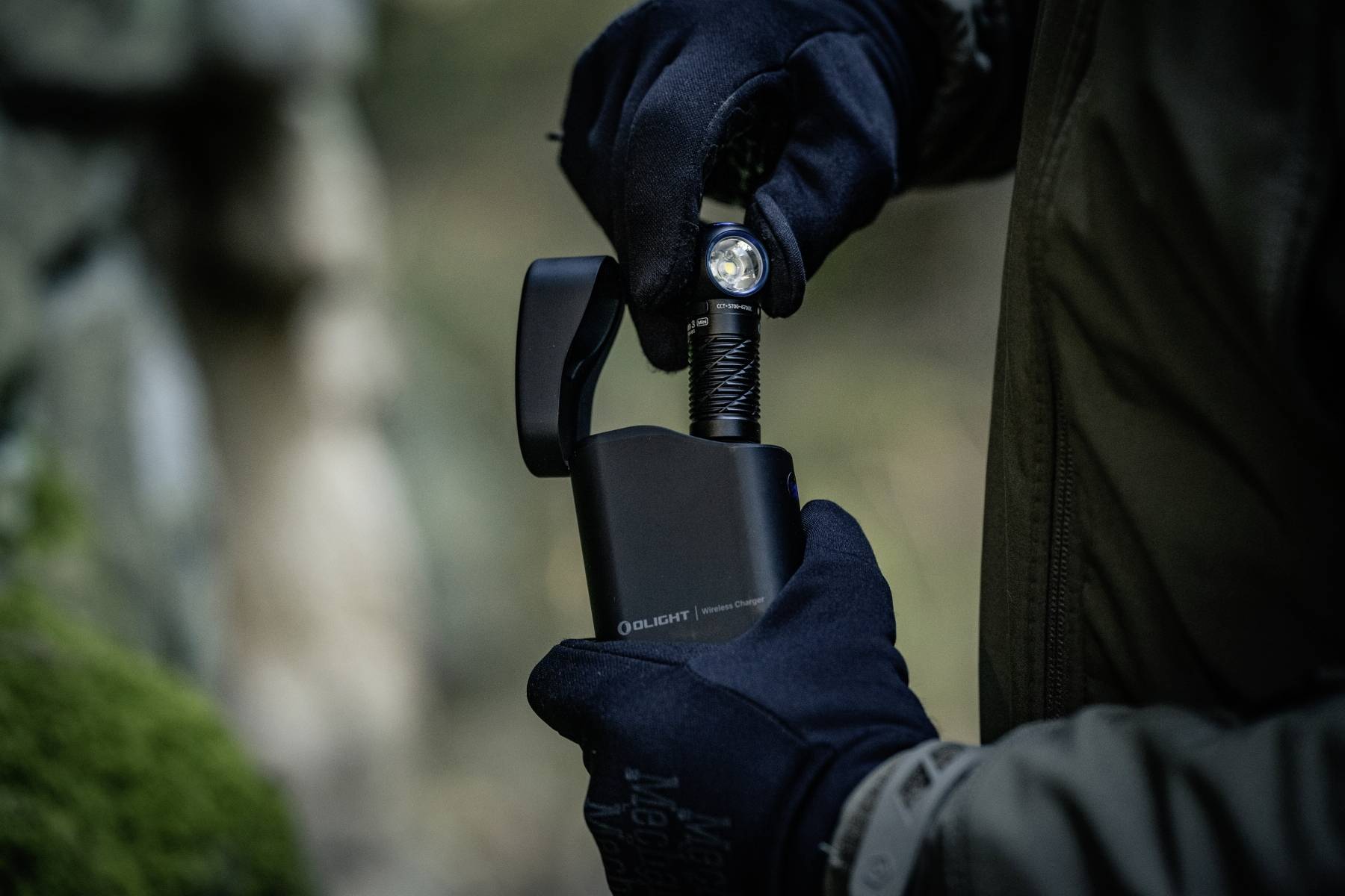 Eine Person mit Handschuhen verwendet eine schwarze Taschenlampe in einer düsteren Außenumgebung. Die Taschenlampe ist hell und betont ihre Funktionalität.