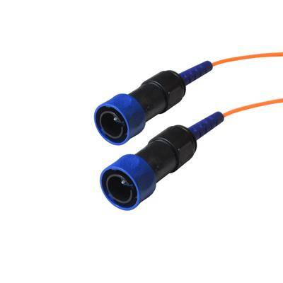 Zwei blaue und schwarze Glasfaserverbinder mit angeschlossenen orangefarbenen Kabeln. Die Verbinder sind nebeneinander positioniert.