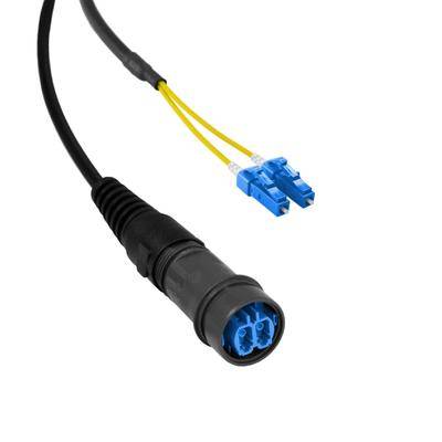 Ein Glasfaserkabel mit einer schwarzen Schutzummantelung ist an beiden Enden mit zwei blauen Steckverbindern verbunden, die für die Datenübertragung konzipiert sind.