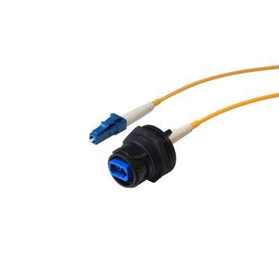 Orangefarbenes Glasfaserkabel mit einem blauen Stecker und einem schwarzen Adapter am Ende, verwendet für Netzwerkverbindungen.